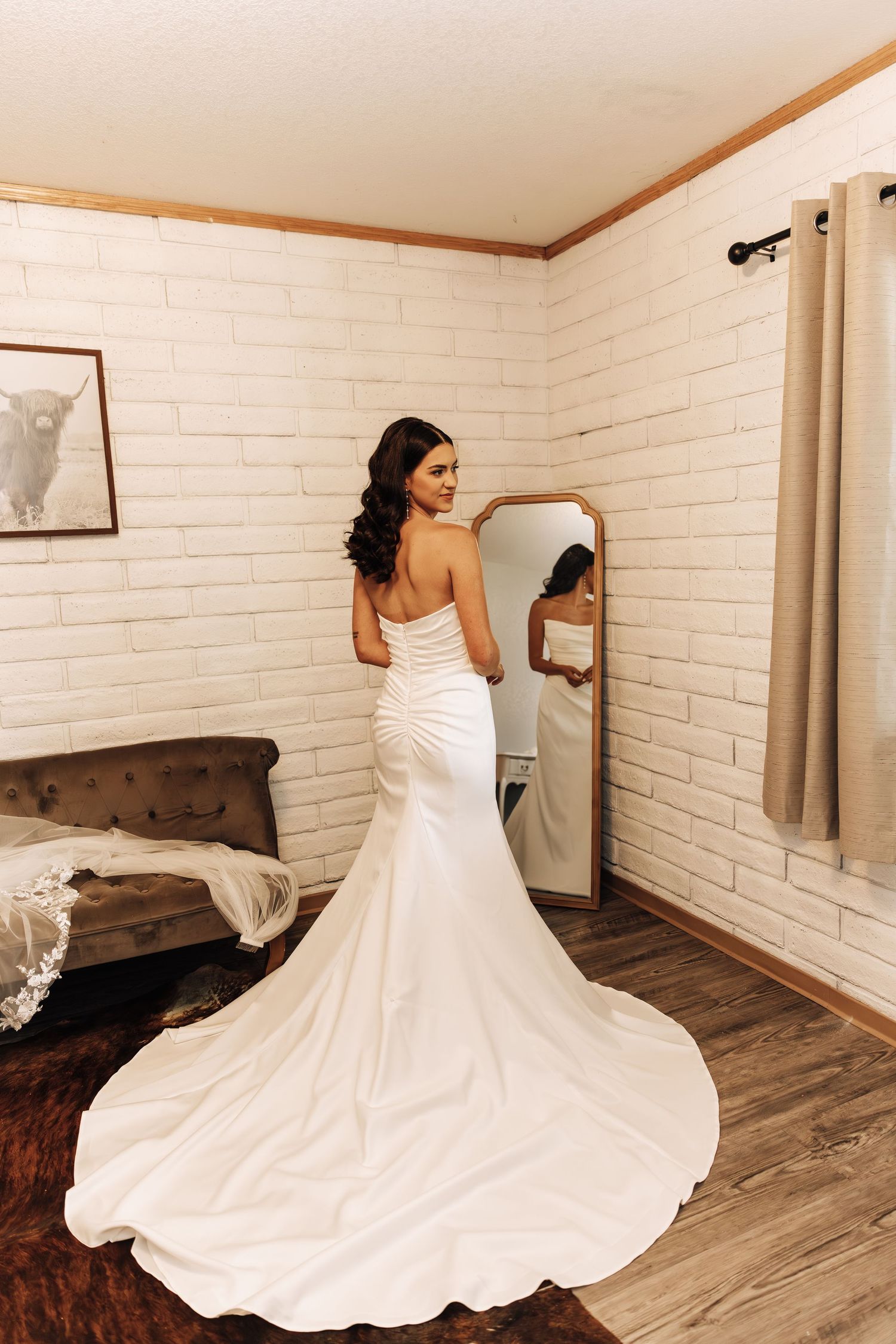 Bride twirling in white wedding gown showing off the flowing skirt against brick wall.