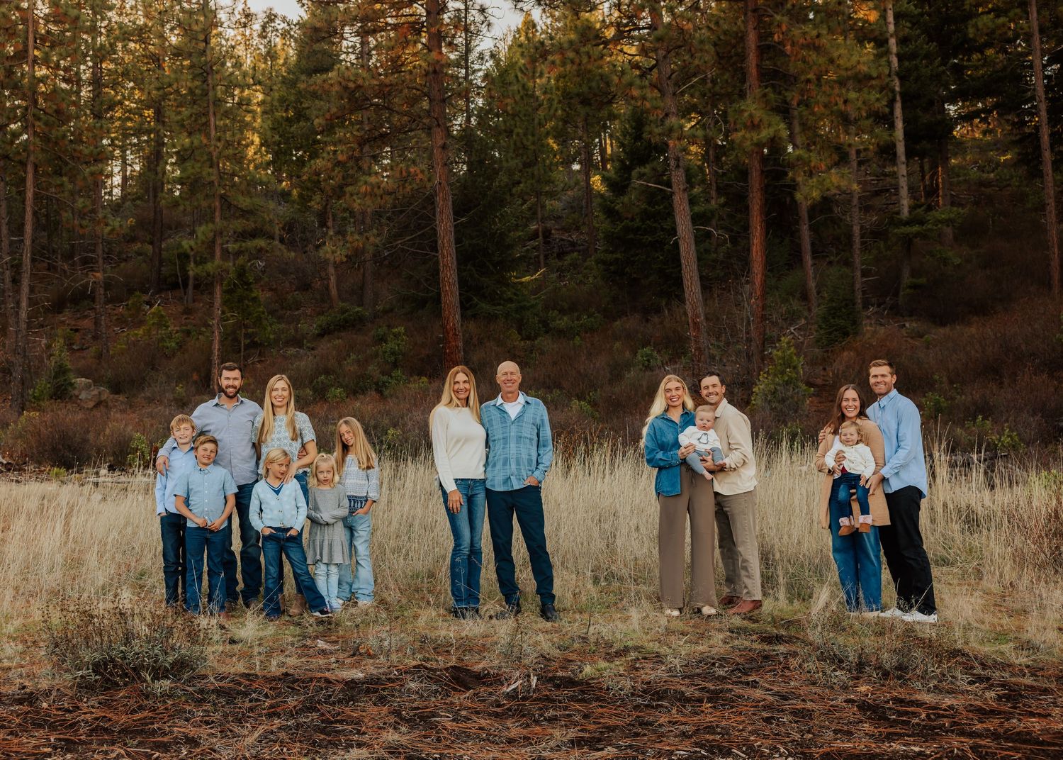 Family portrait session in autumn field with pine trees and golden light.