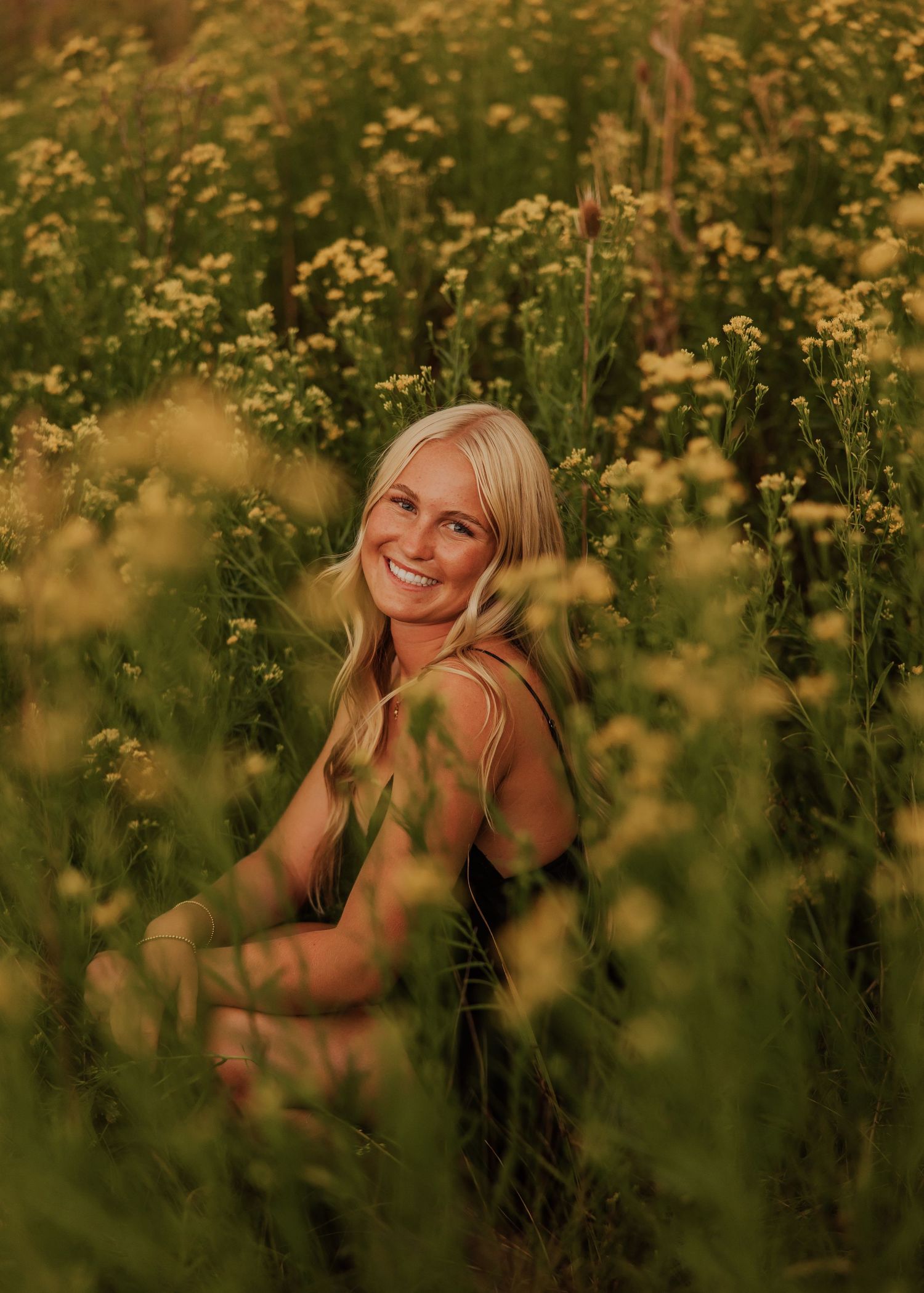 Dreamy summer portrait session in a field of blooming yellow wildflowers.