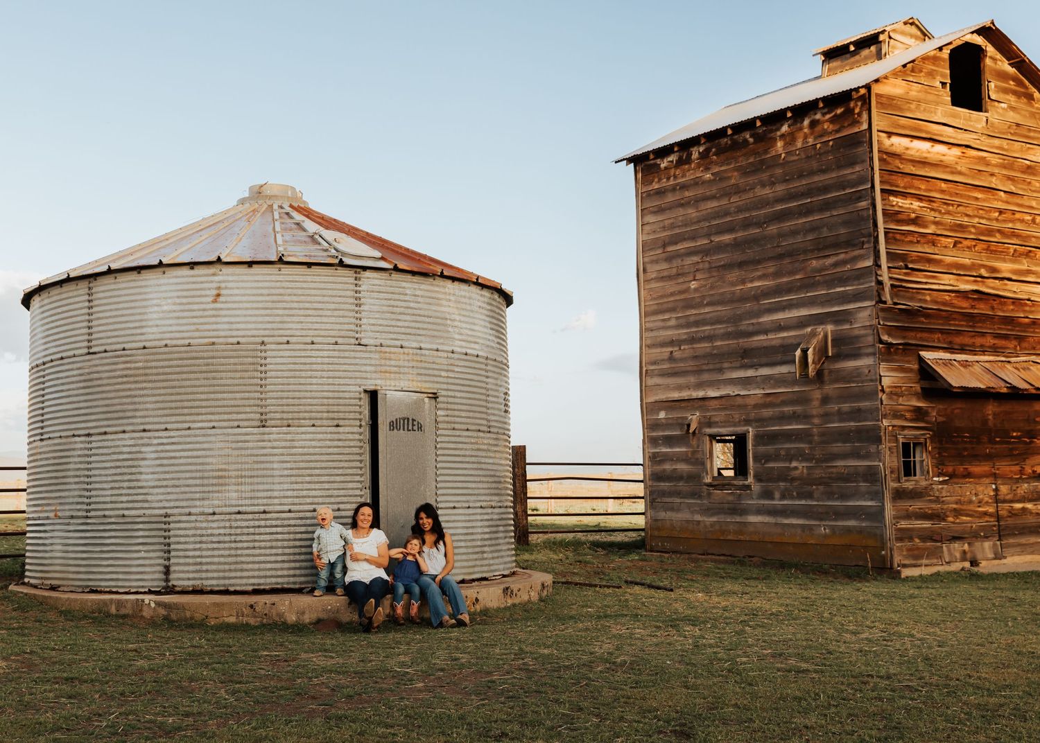 Panoramic view of rustic wooden barns and grain silos at sunset.