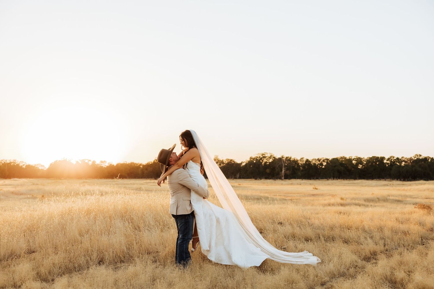 Couple walking through a sun-drenched field at golden hour.