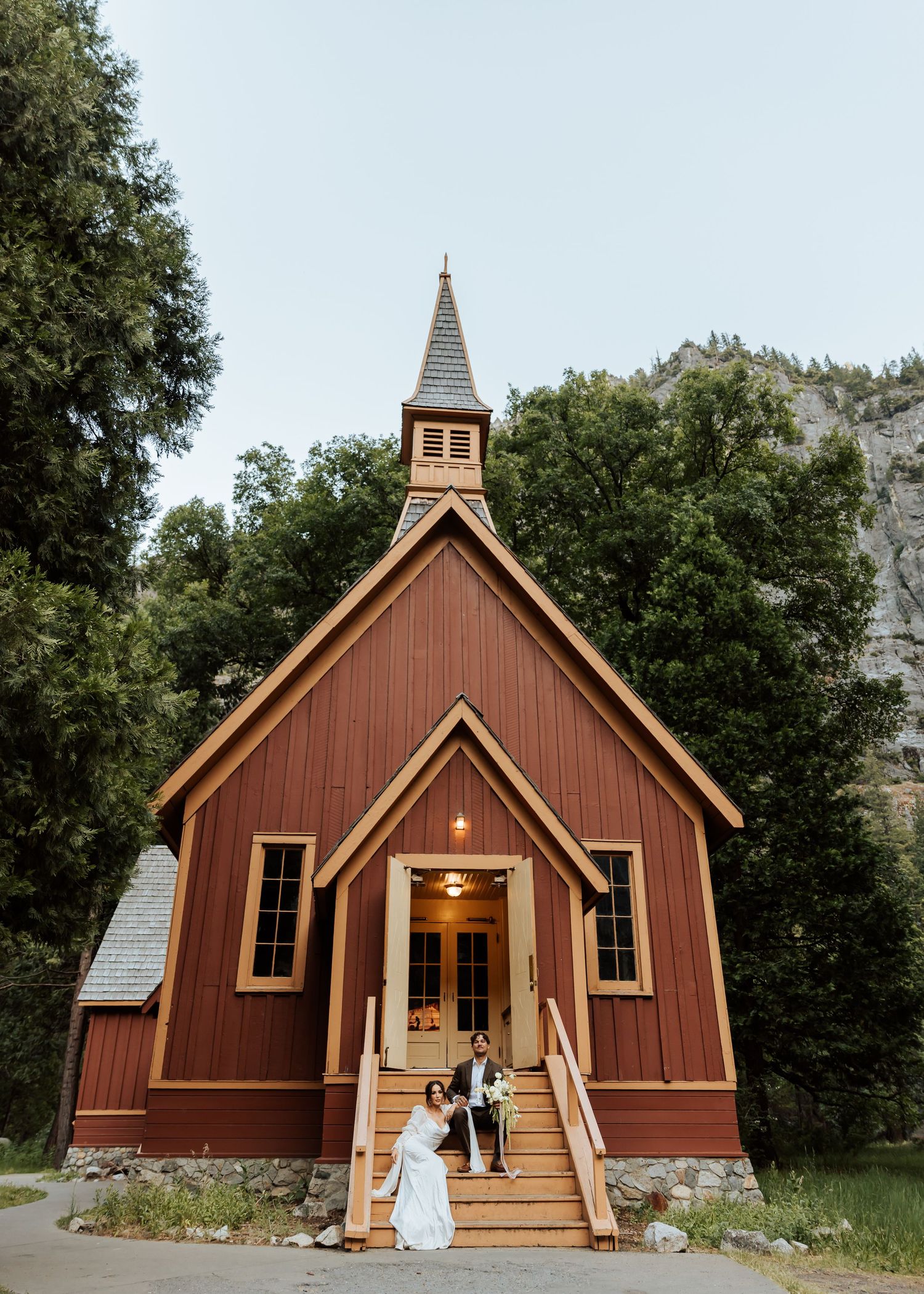 A rustic brown wooden chapel with a tall steeple and front porch shown in three different angles against a wooded backdrop.