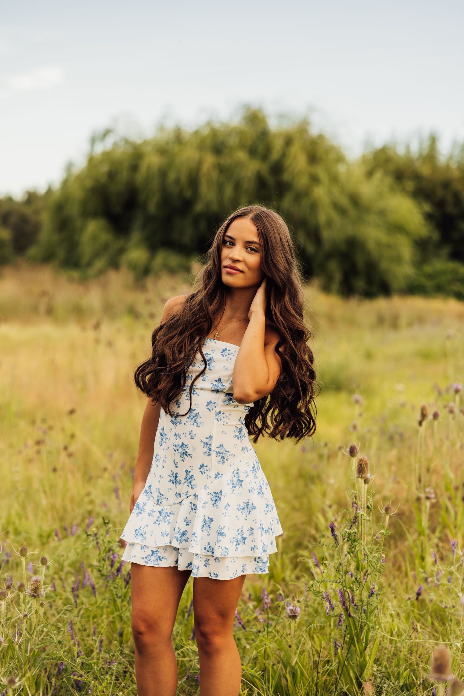 A floral sundress-clad figure dances playfully in a golden summer meadow at sunset.