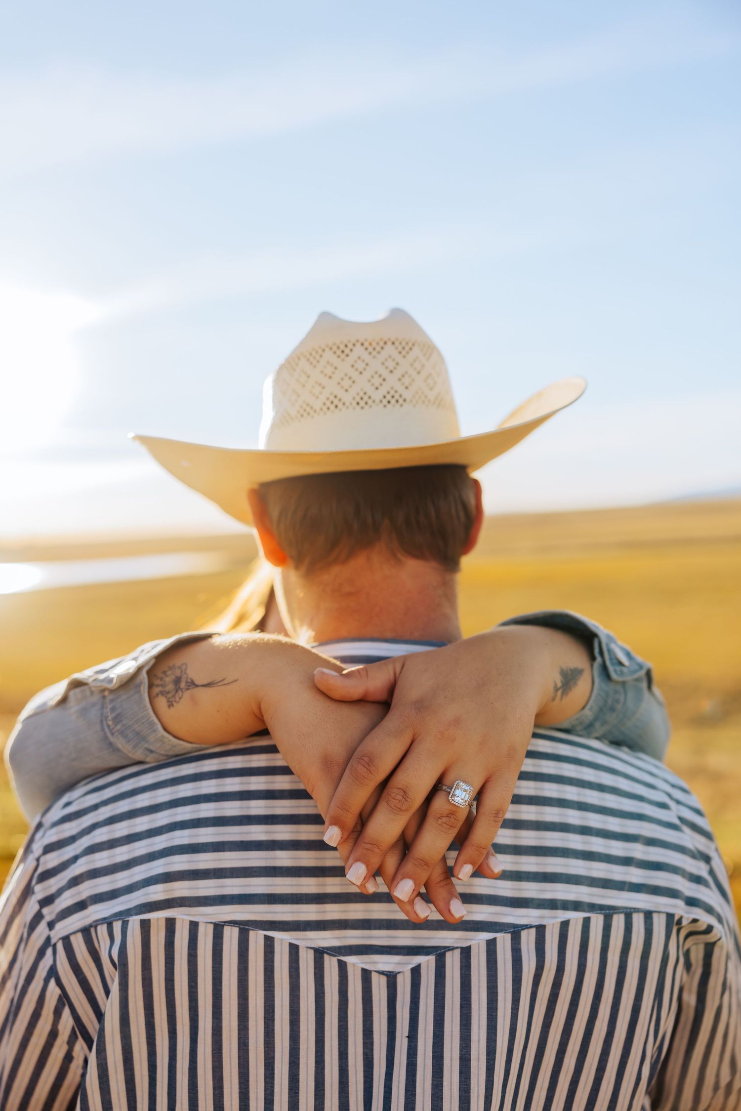 A close-up shot showing hands wrapped around shoulders in a striped shirt.