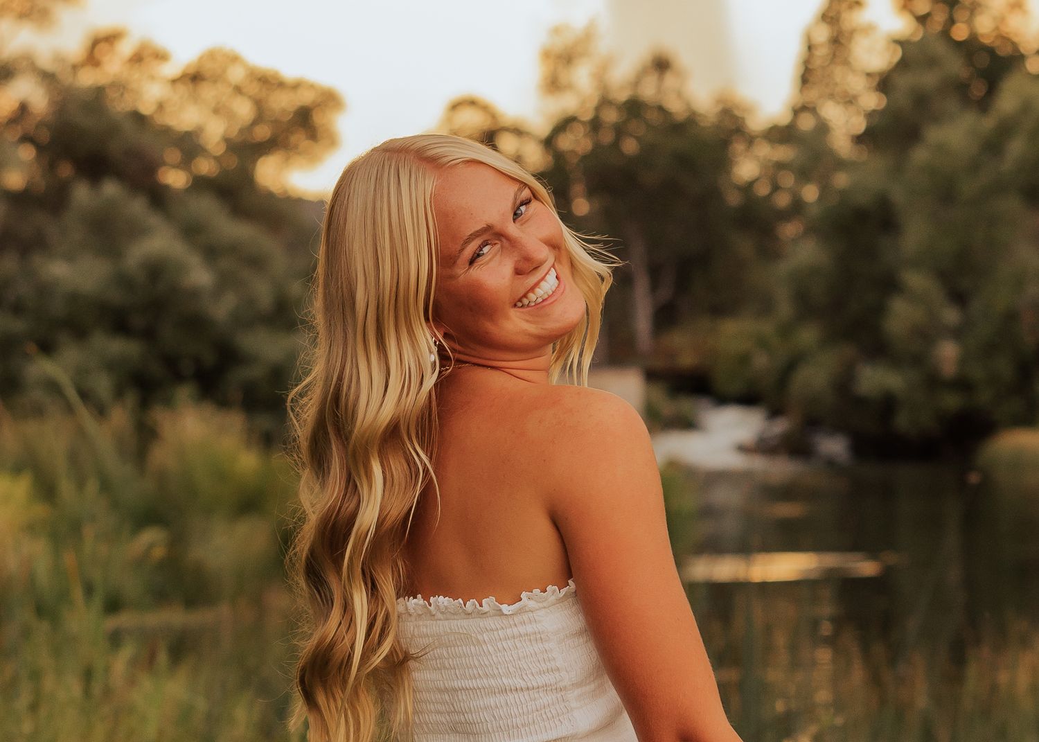 Golden hour portraits by a lake with white summer dress and natural scenery.
