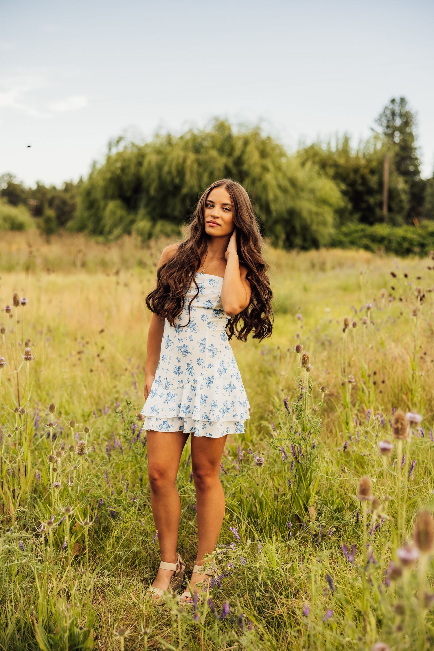 Summer fashion photography in wildflower field with floral print romper.