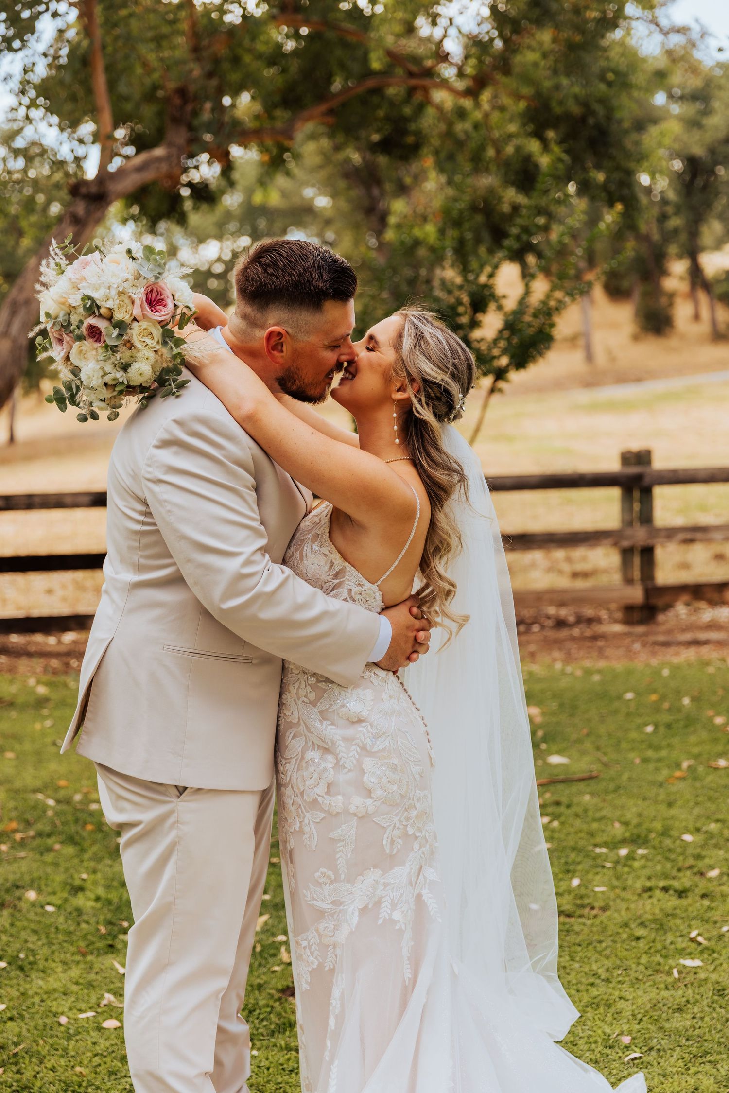 Romantic couple shares intimate moment in outdoor garden setting during wedding photoshoot.