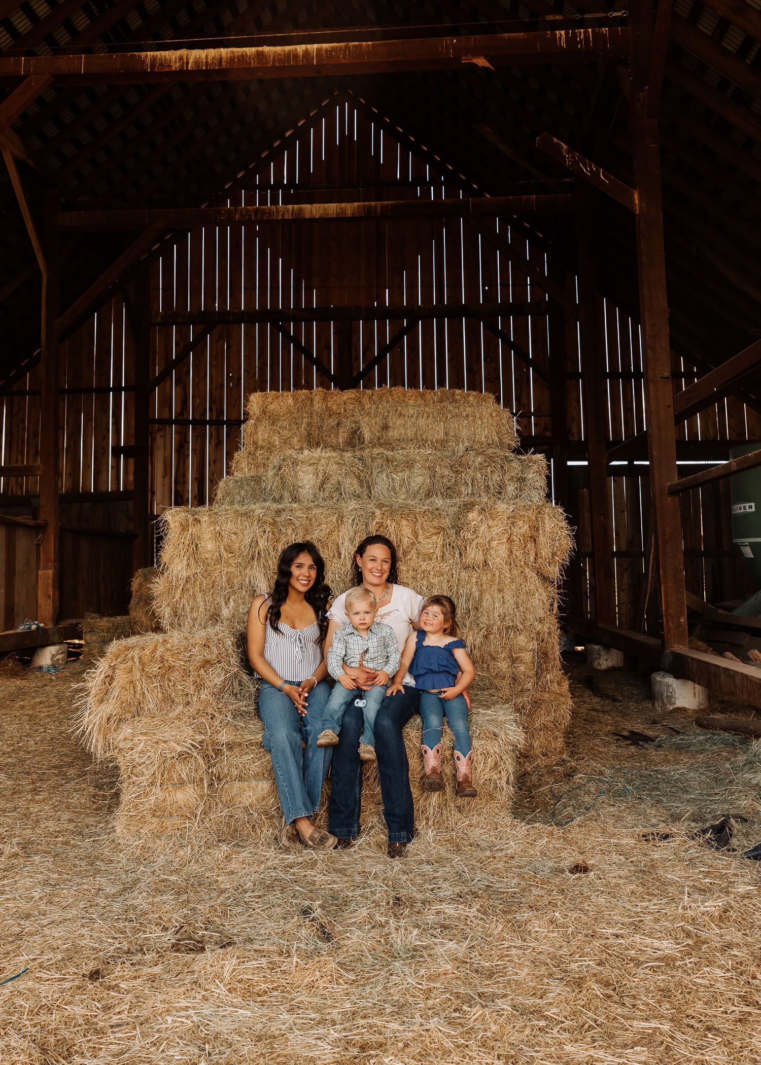 A cozy family photo session inside a rustic barn with hay bales.