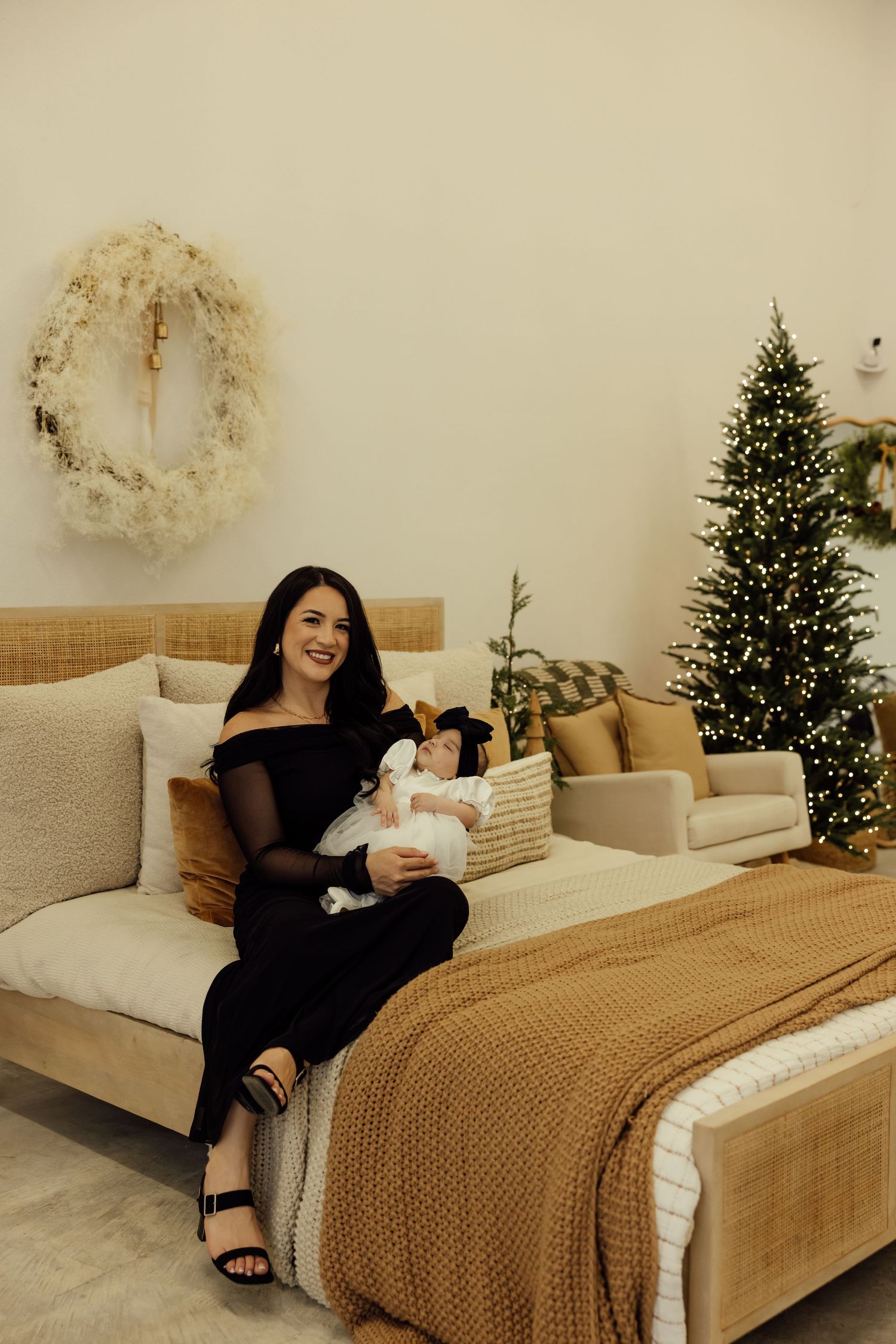 Cozy bedroom scene with Christmas tree and neutral decor in warm tones.