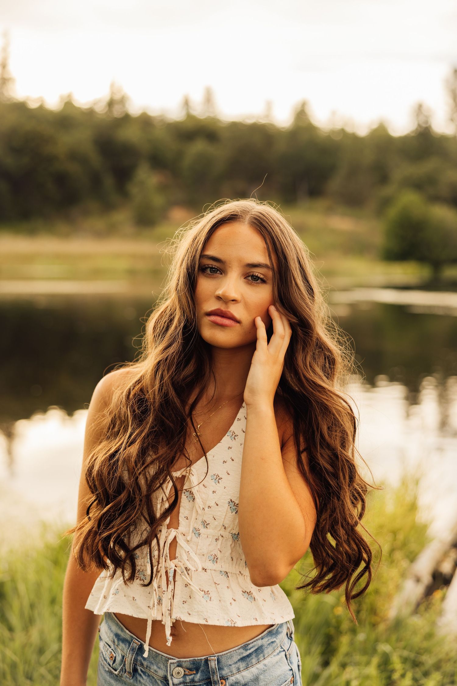 Sunset portrait session by a lake featuring white lace crop top and natural lighting.