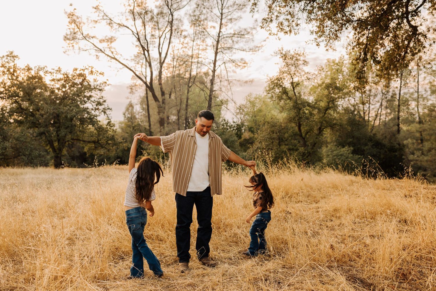 Children playing together in a sun-drenched meadow with trees in background.