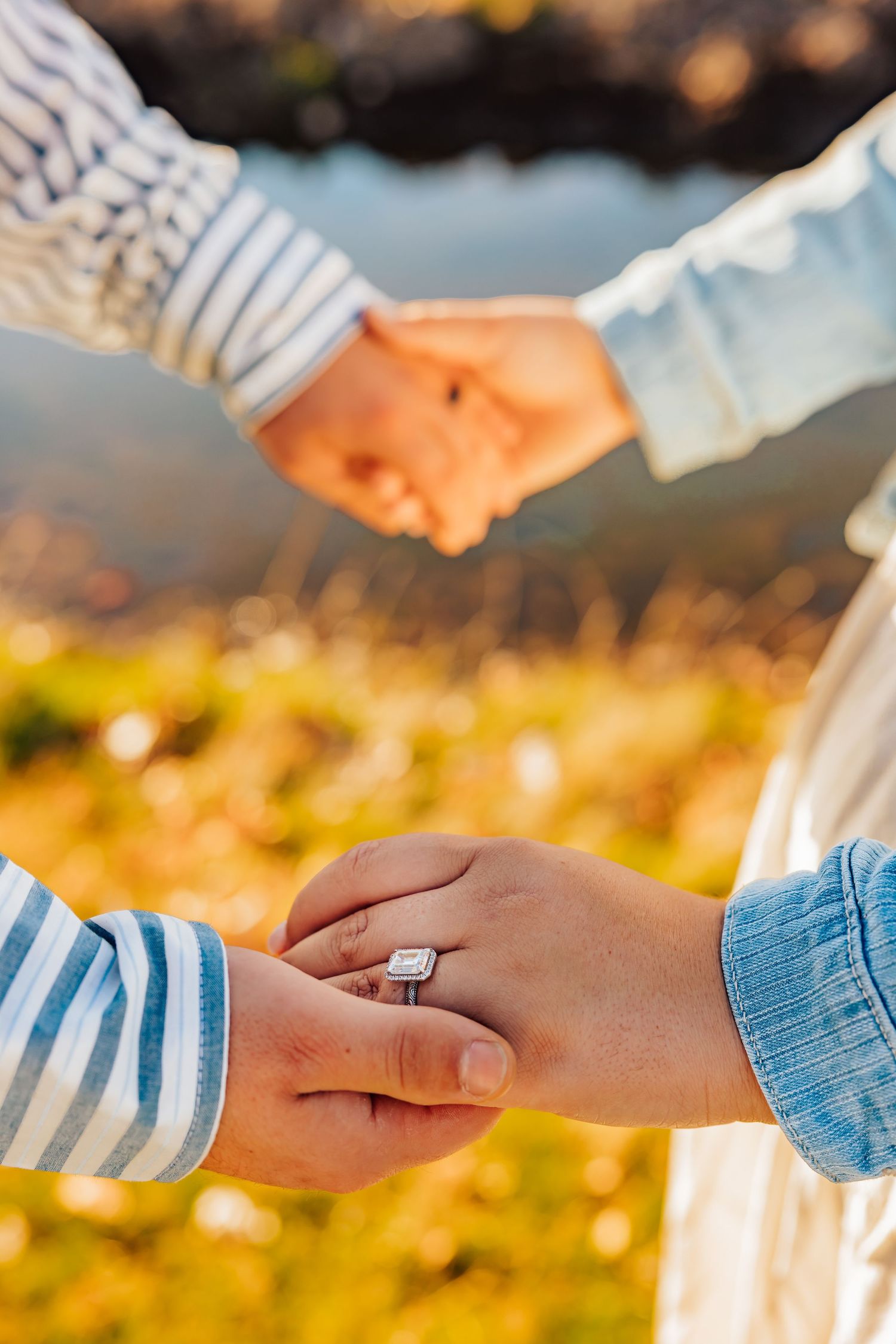 Close-up of hands holding during sunset with an engagement ring visible.