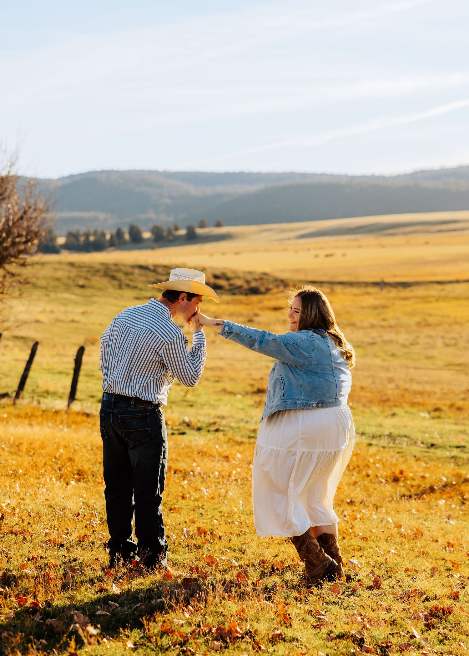 A romantic photoshoot in a golden prairie field with mountains in the background.