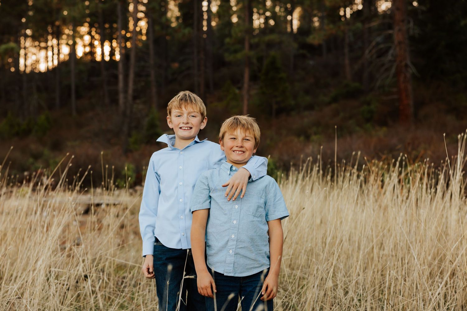 Casual family photo session with siblings in coordinating blue outfits at sunset.