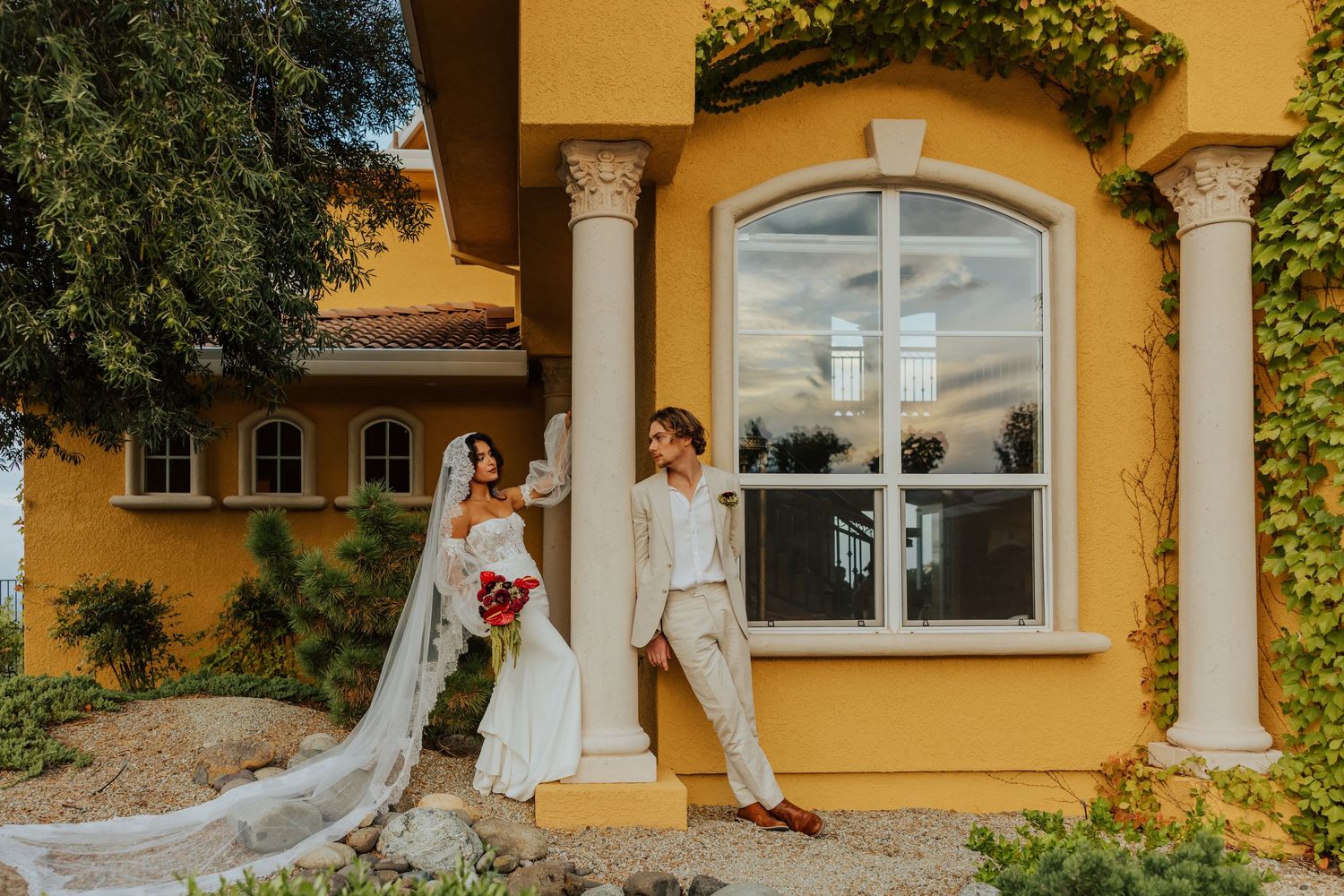 Yellow Mediterranean style villa with ornate columns and climbing vines creates a romantic outdoor setting.
