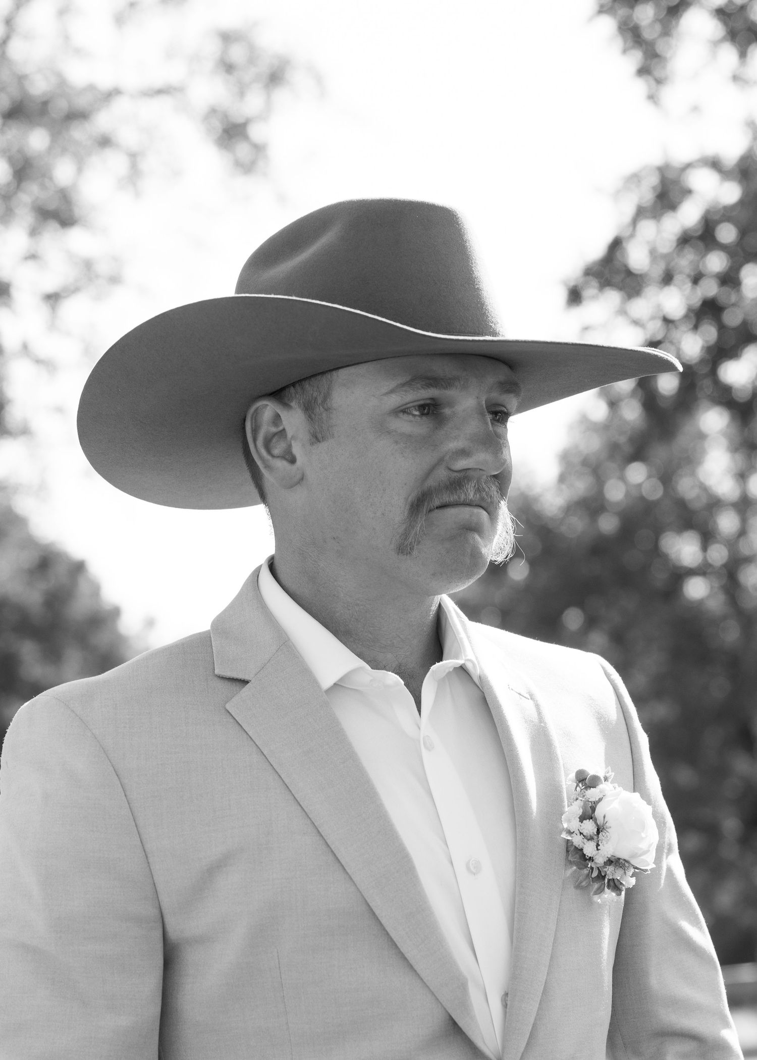 Black and white portraits of groom wearing cowboy hat and light colored suit.
