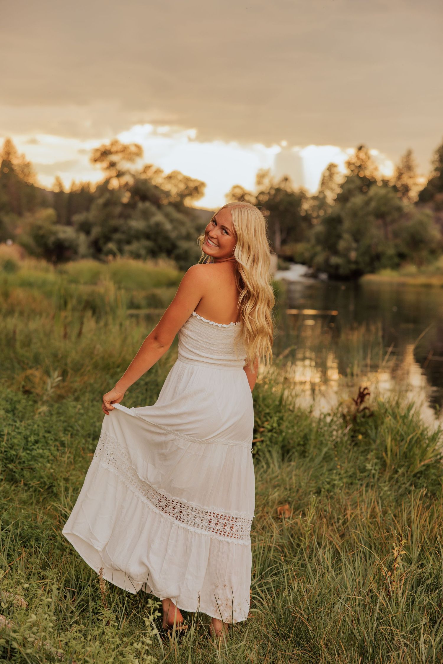 White flowy dress twirling photo session by a lake during sunset.