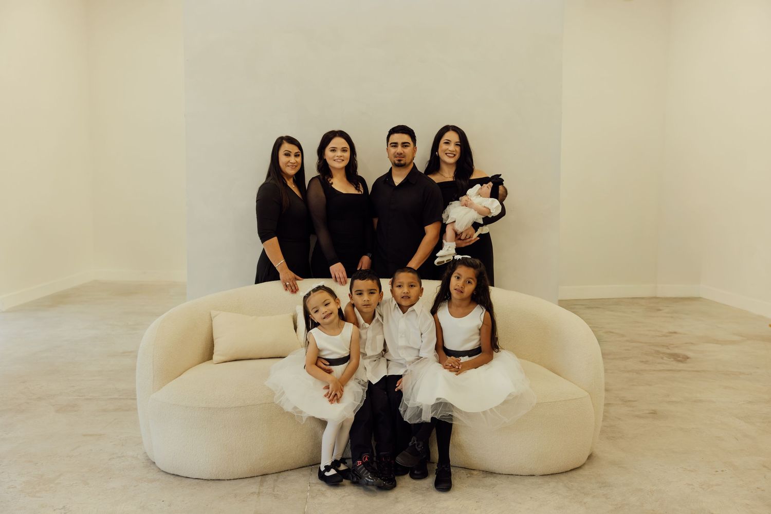 Group portrait on curved white sofa with Christmas decorations in background.