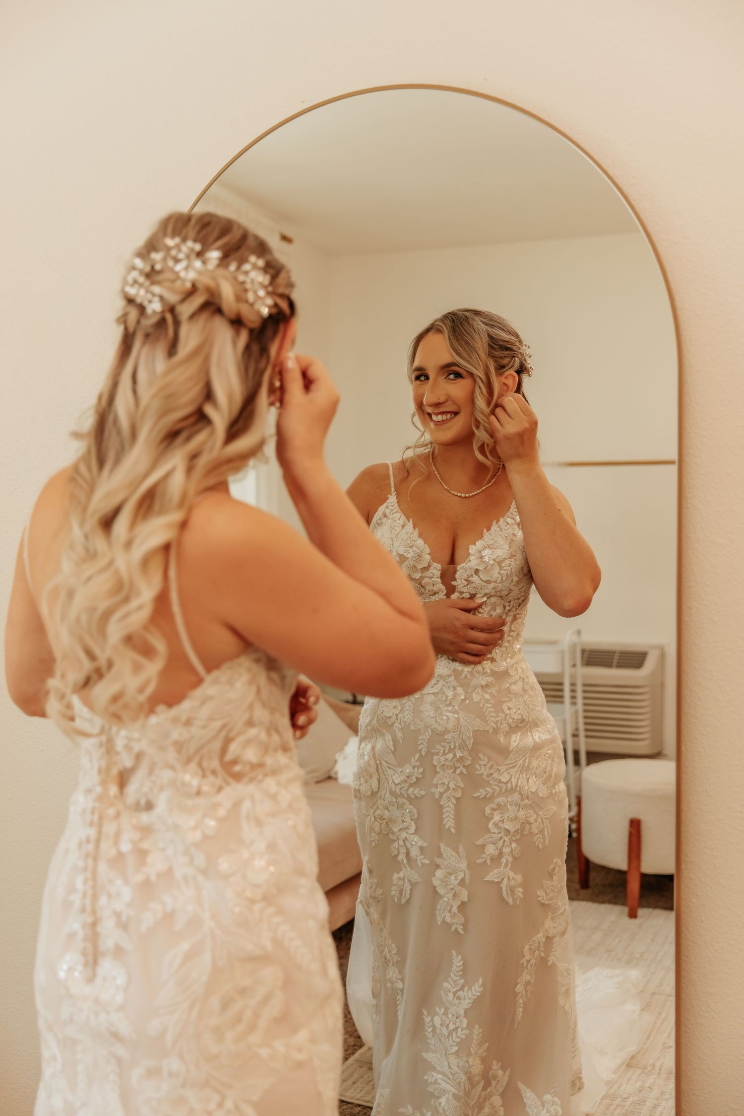 A bride getting ready in an elegant lace wedding gown with intricate details and beading.