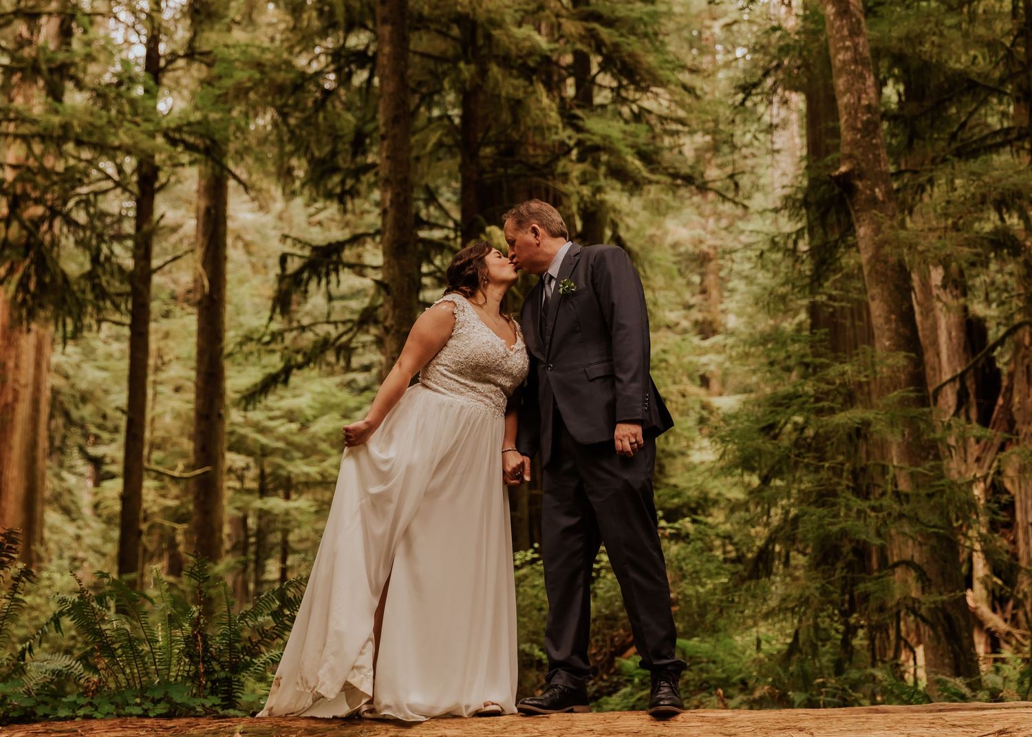 A panoramic forest wedding scene with couples and guests gathered among ancient redwood trees.