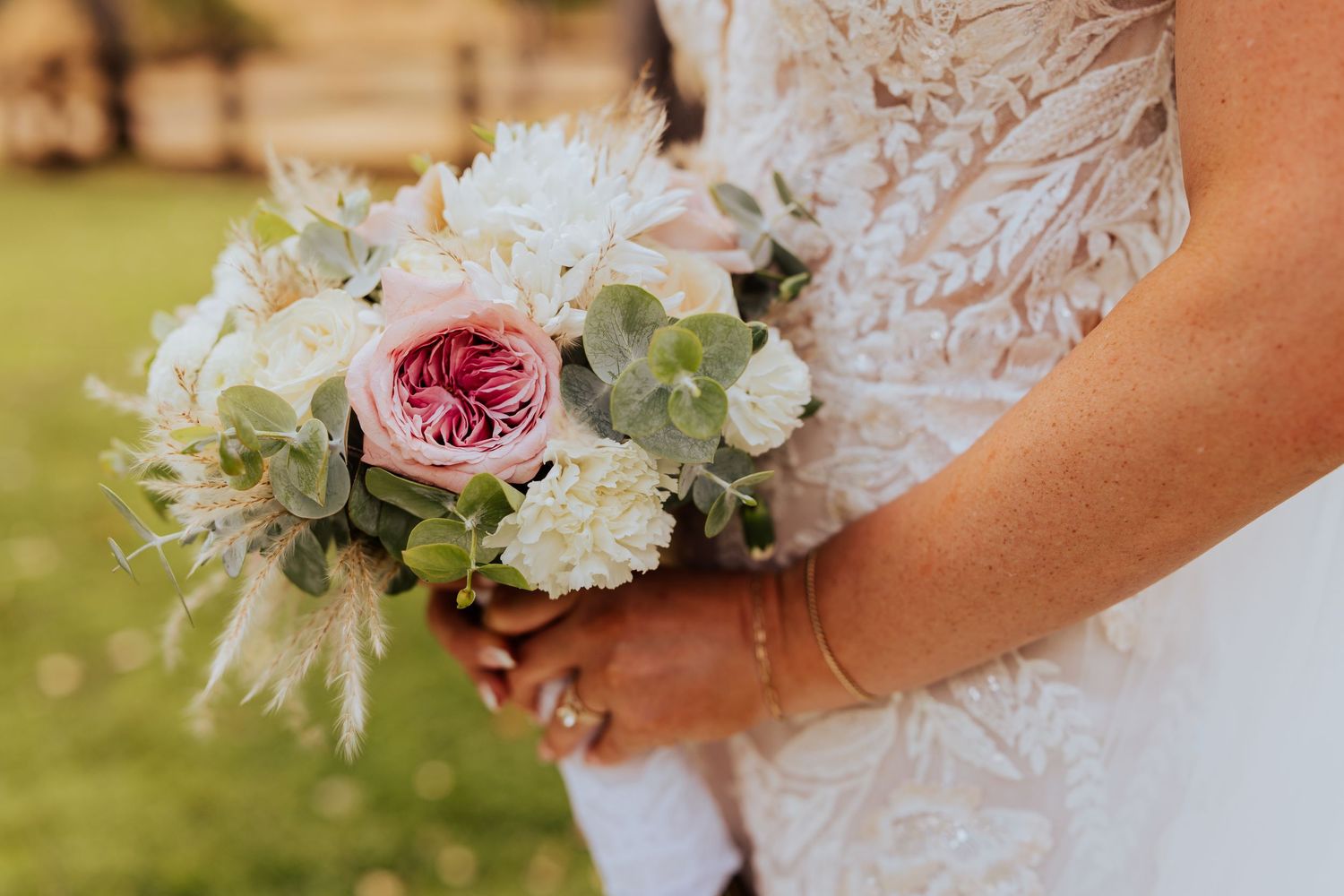 Close-up of a bridal bouquet featuring pink roses and white flowers with eucalyptus leaves.