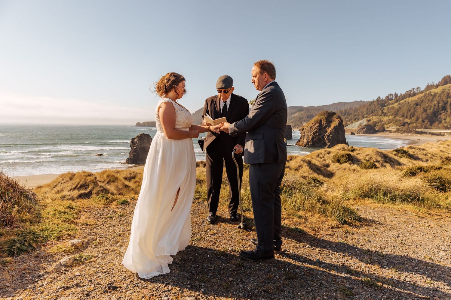 An intimate wedding ceremony takes place on a scenic overlook with waves crashing below.