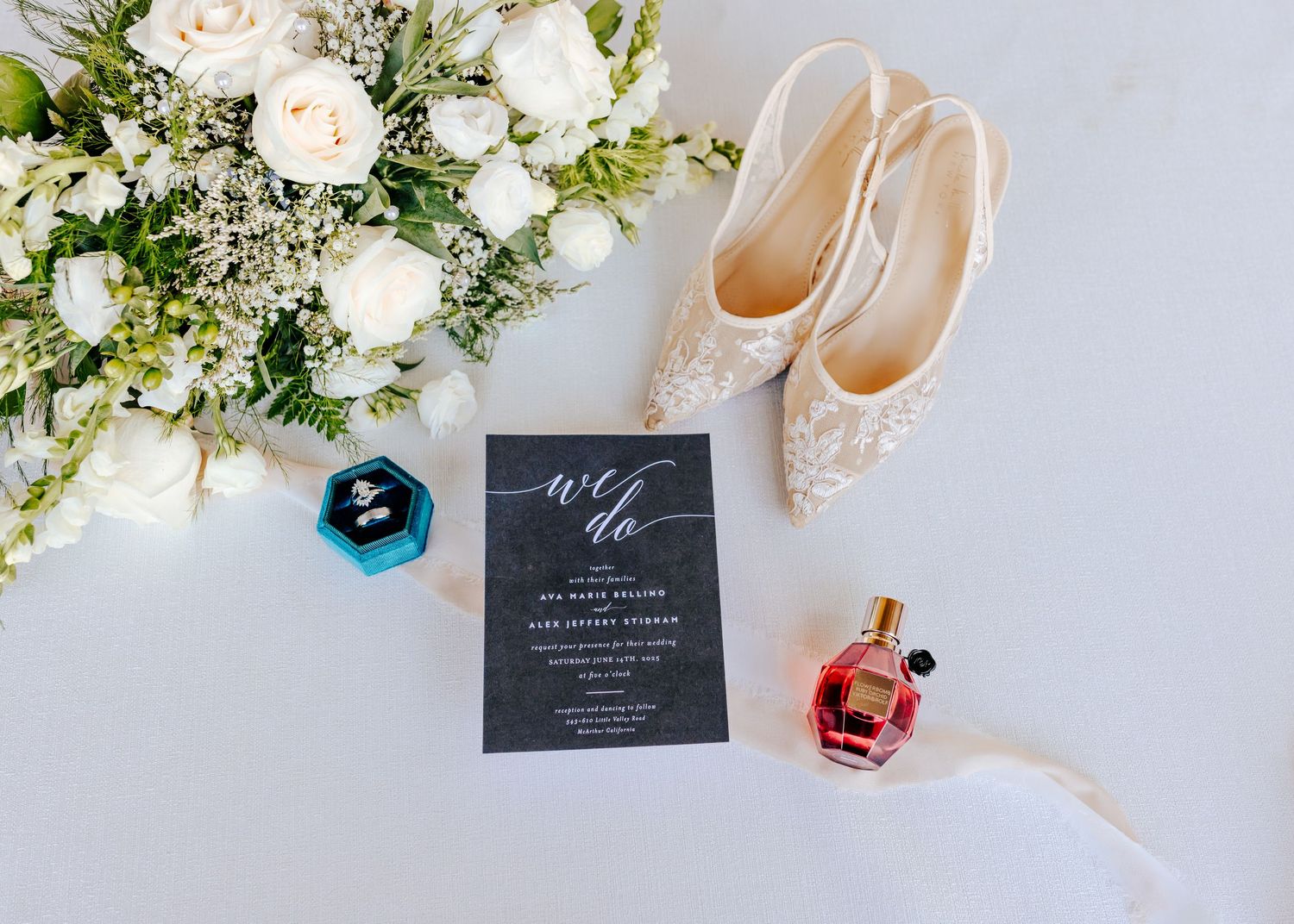 Wedding details including white floral arrangements, invitations and bridal accessories on light background.