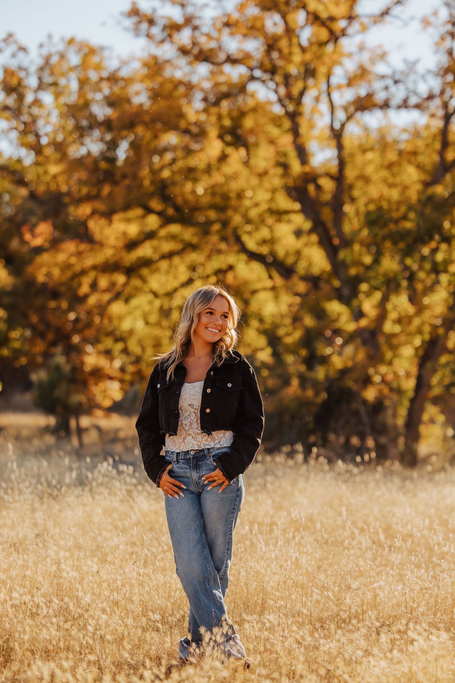 Candid autumn photoshoot in a field with golden trees and natural lighting.