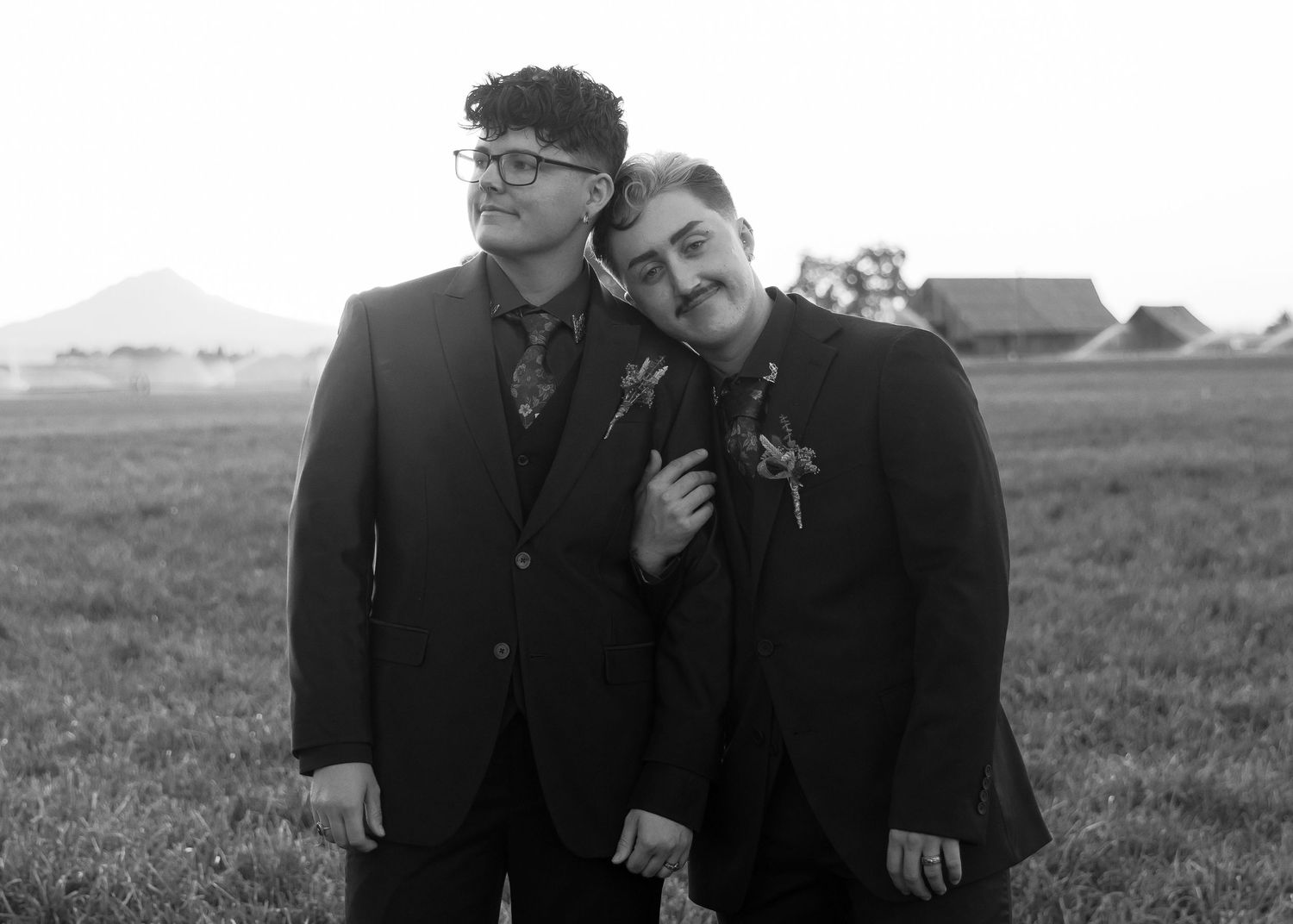 Wedding party members in formal attire pose in black and white portrait style.