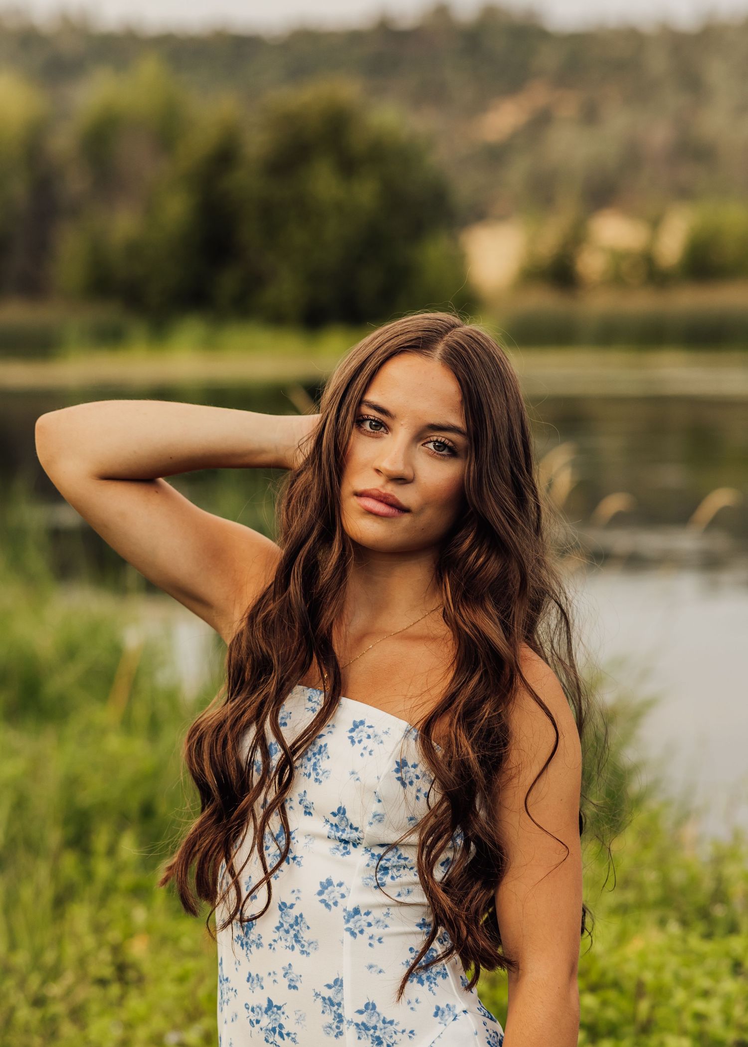 A white and blue floral dress stands out against a serene lakeside background.