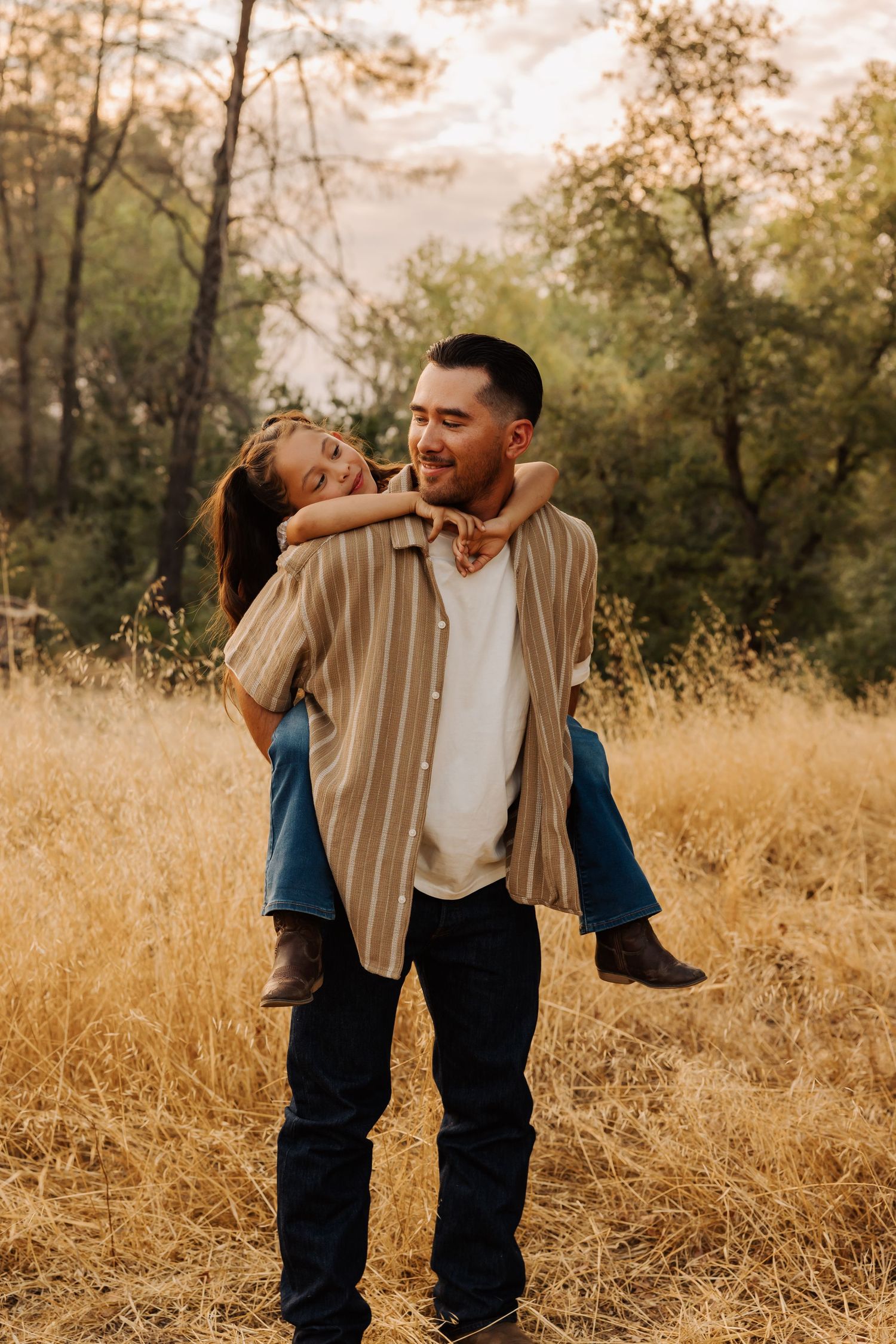 Two siblings share playful moments in a golden field during sunset.