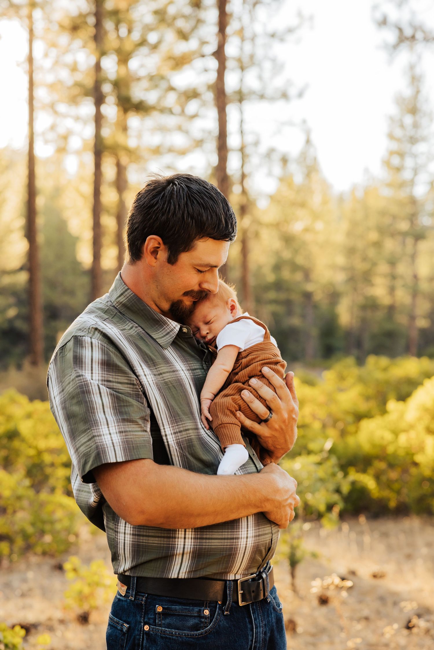 Tender moments shared between family members in sunlit forest setting.