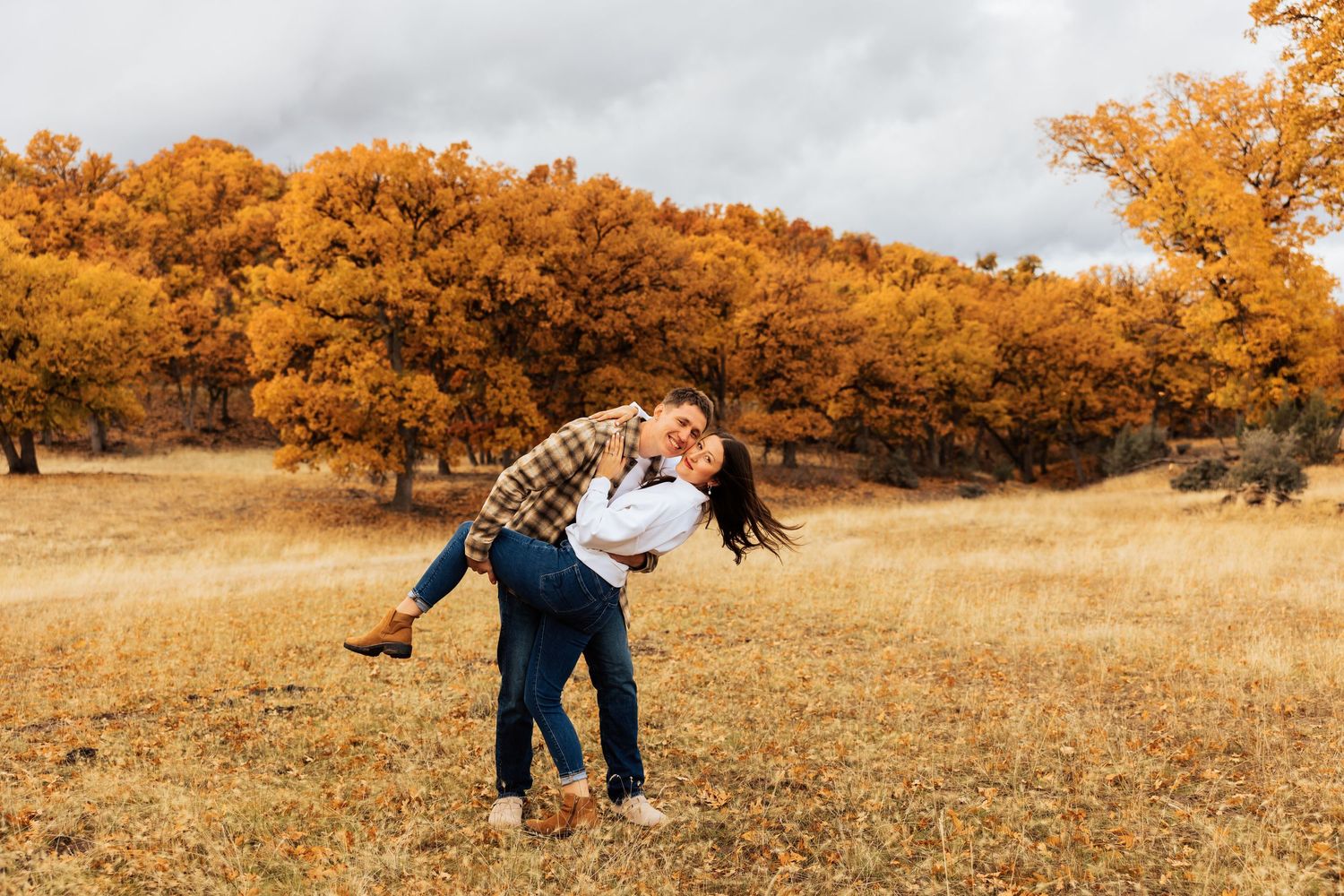 Panoramic view of a couple's photoshoot in a golden autumn landscape.