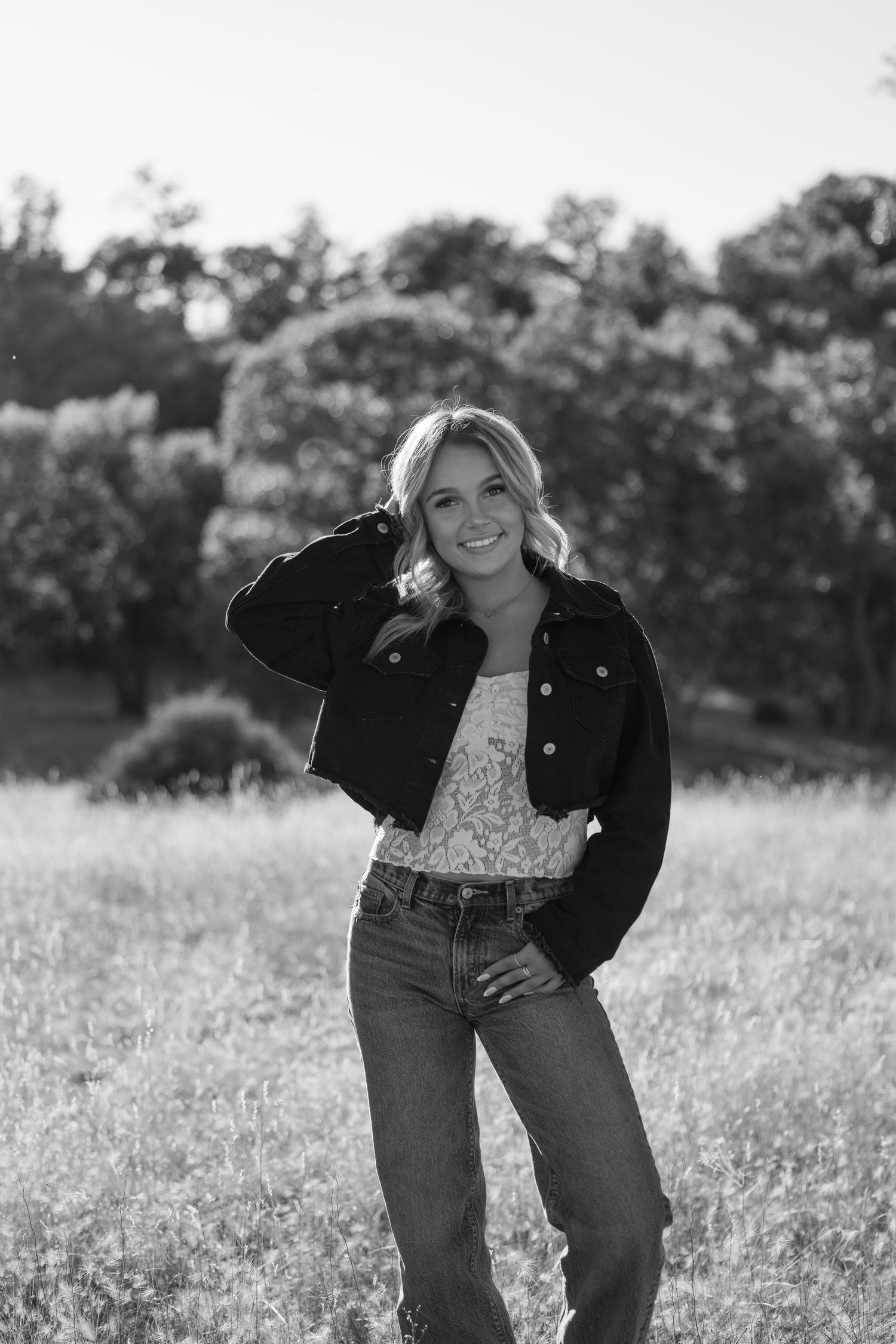 Casual black and white portrait featuring denim and a jacket in a wildflower field.