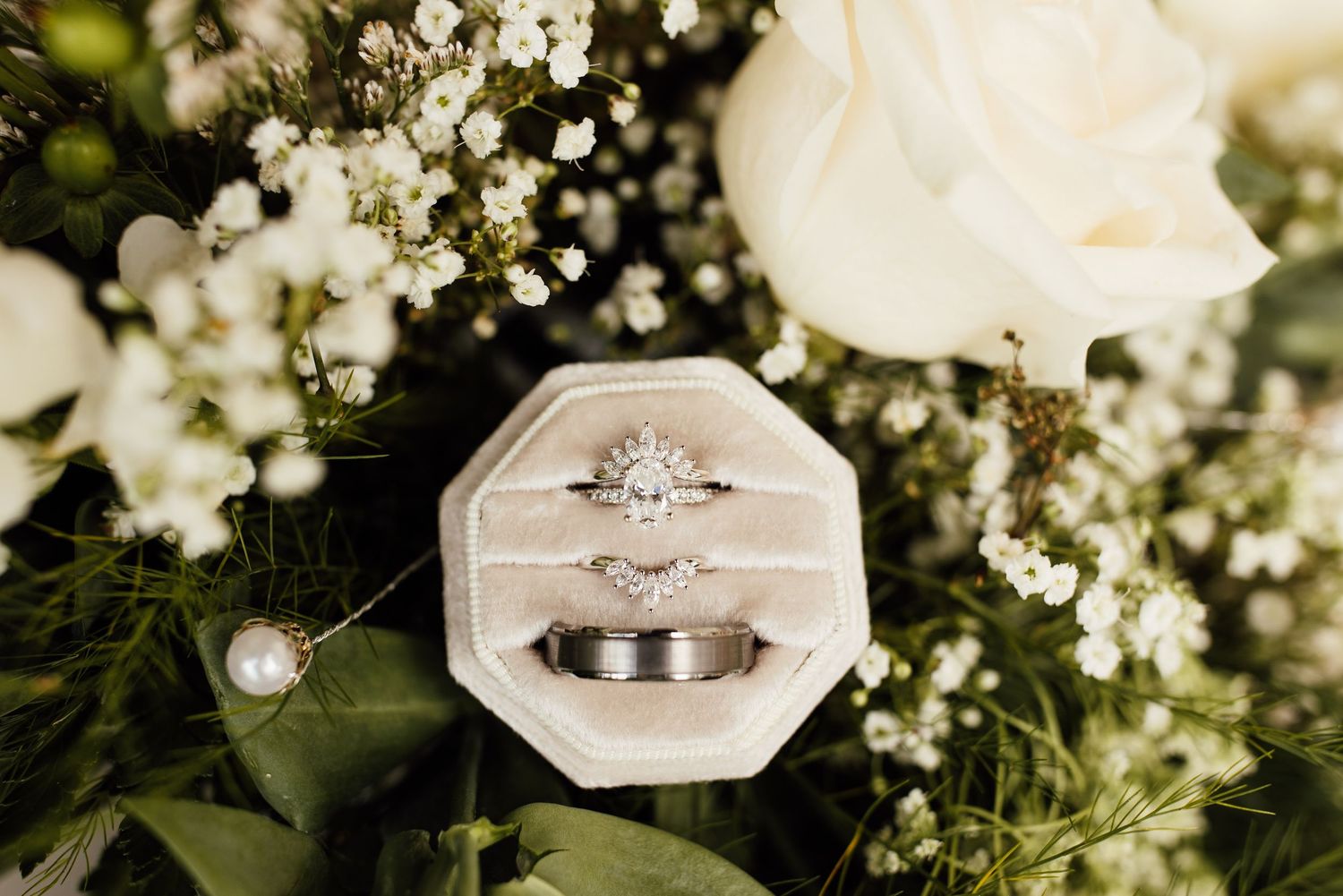Wedding rings nestled among delicate white flowers and greenery.