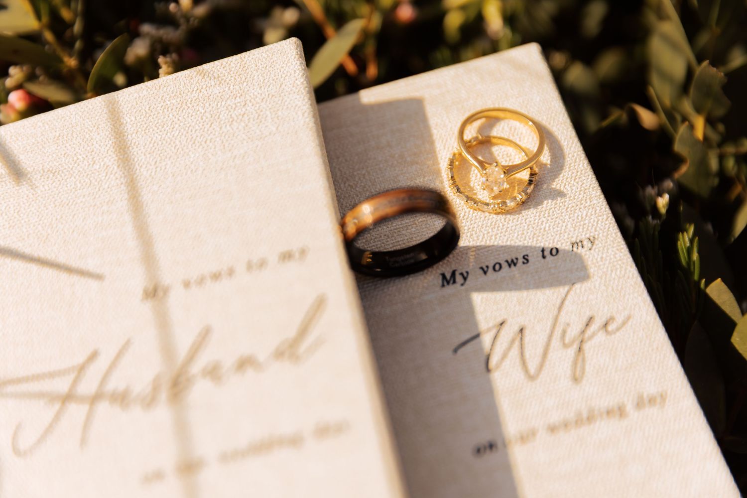 Wedding rings rest on an open vow book with elegant gold lettering.