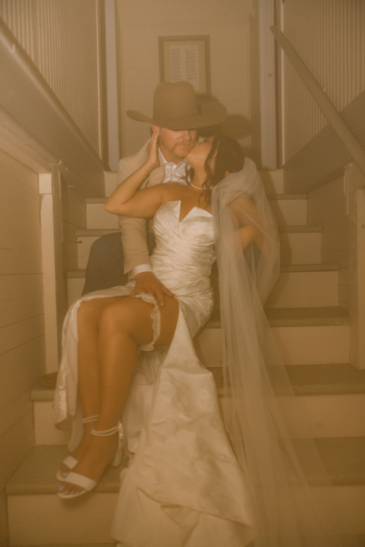 Intimate wedding portrait showing a couple seated on stairs in warm sepia tones.