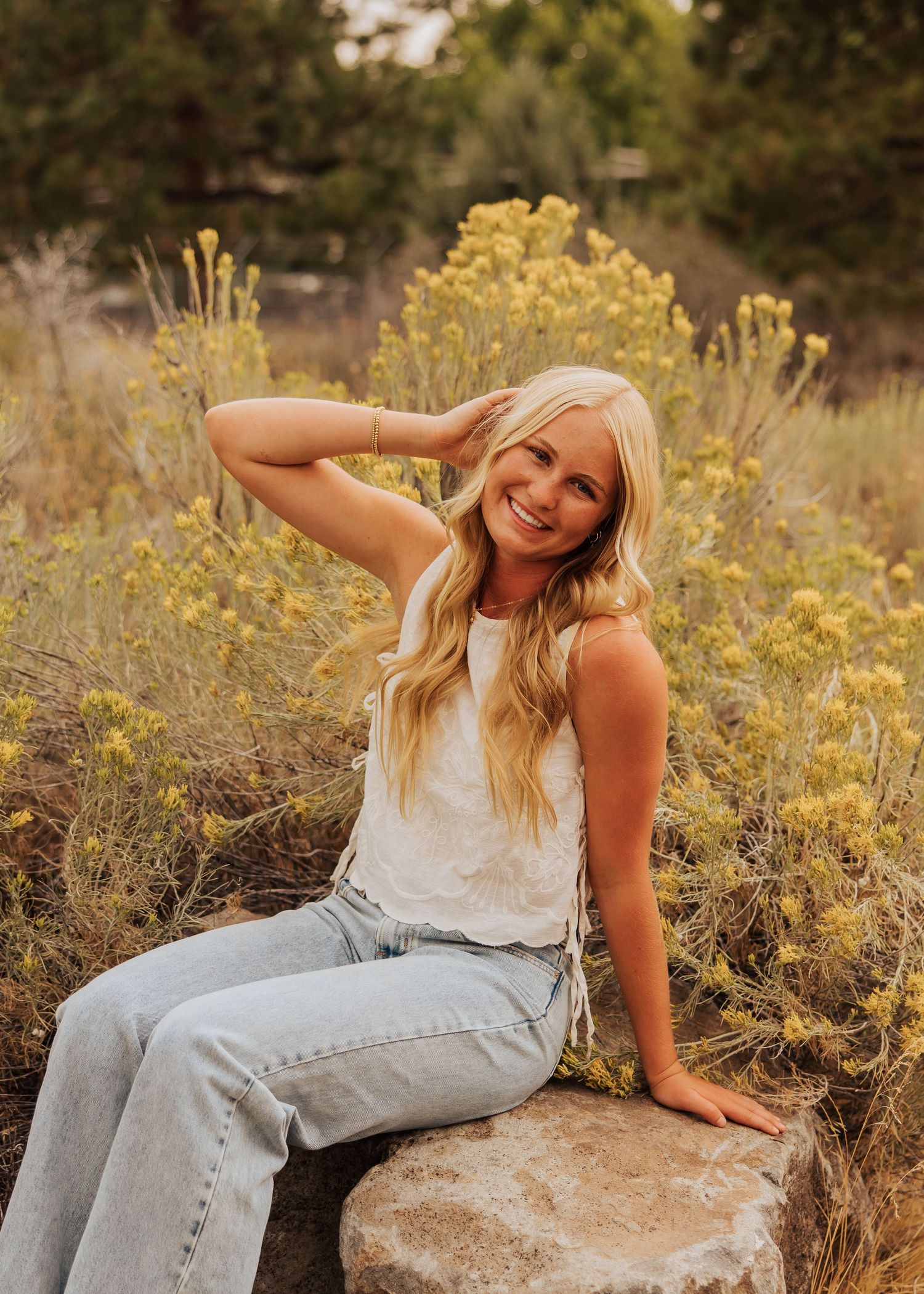 Natural outdoor portrait session featuring light denim and white top against desert brush.