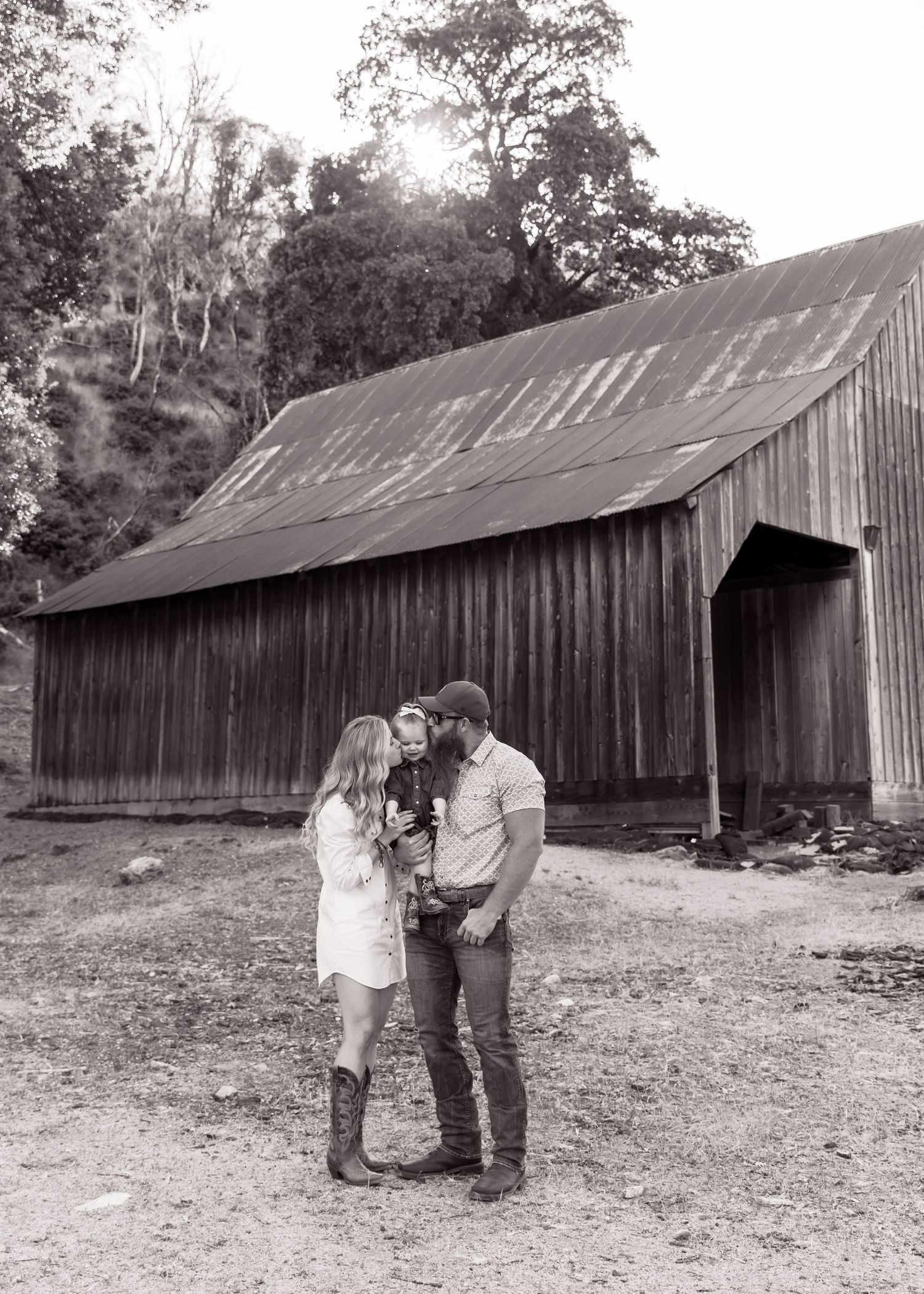 A romantic photoshoot in front of a rustic wooden barn with natural lighting.