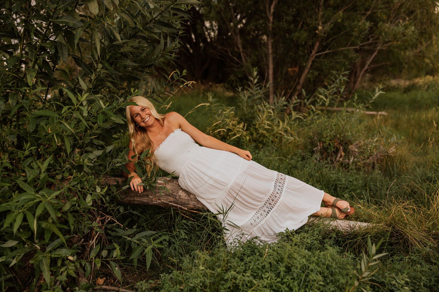 A white sundress flows in the golden light near a serene lake during sunset.