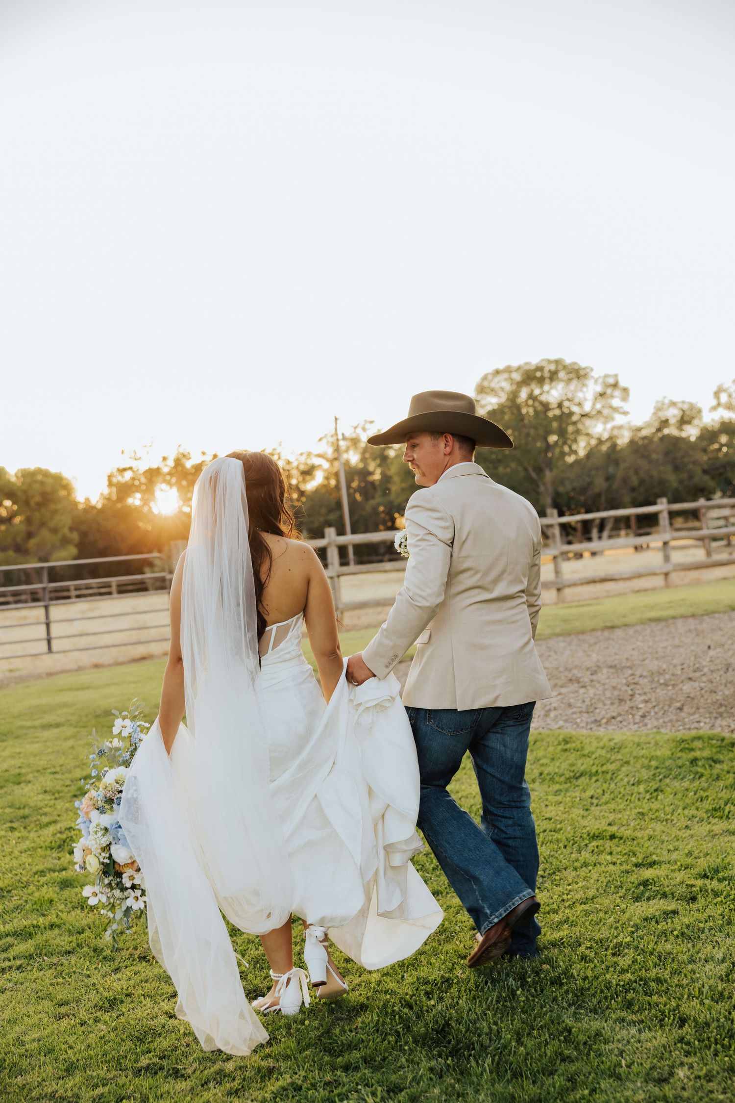 Wedding couple walking on grass with white dress flowing in the breeze.