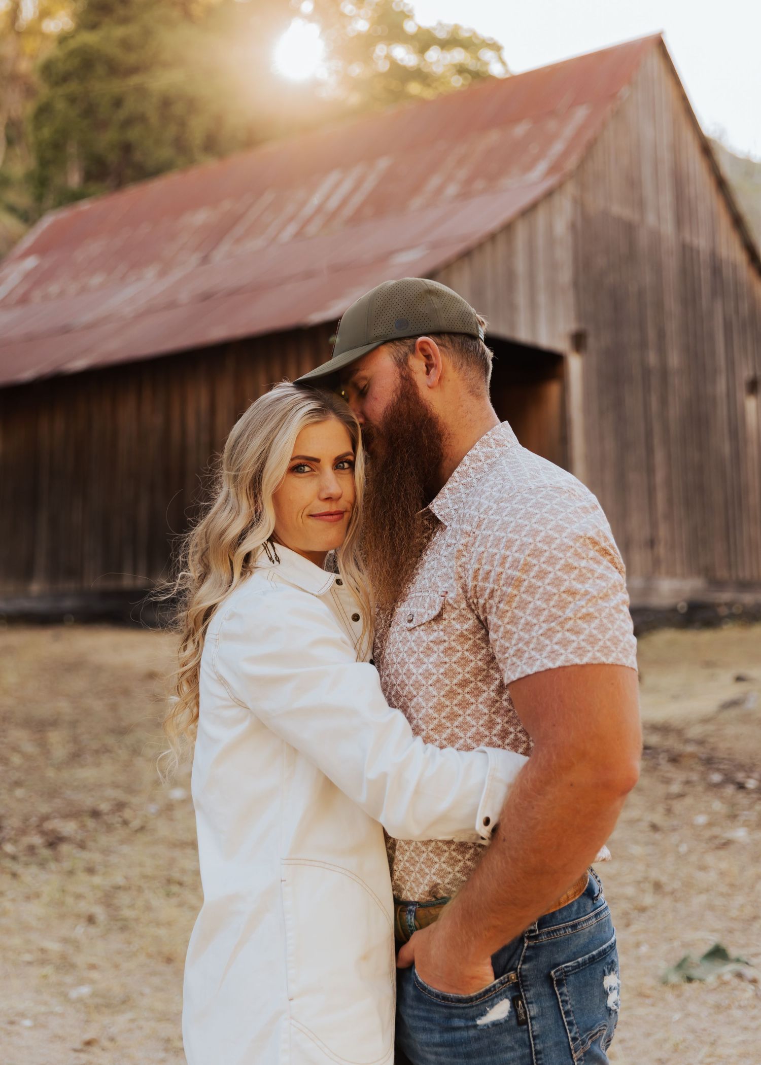 Sweet romantic moment captured in front of a rustic barn during golden hour.