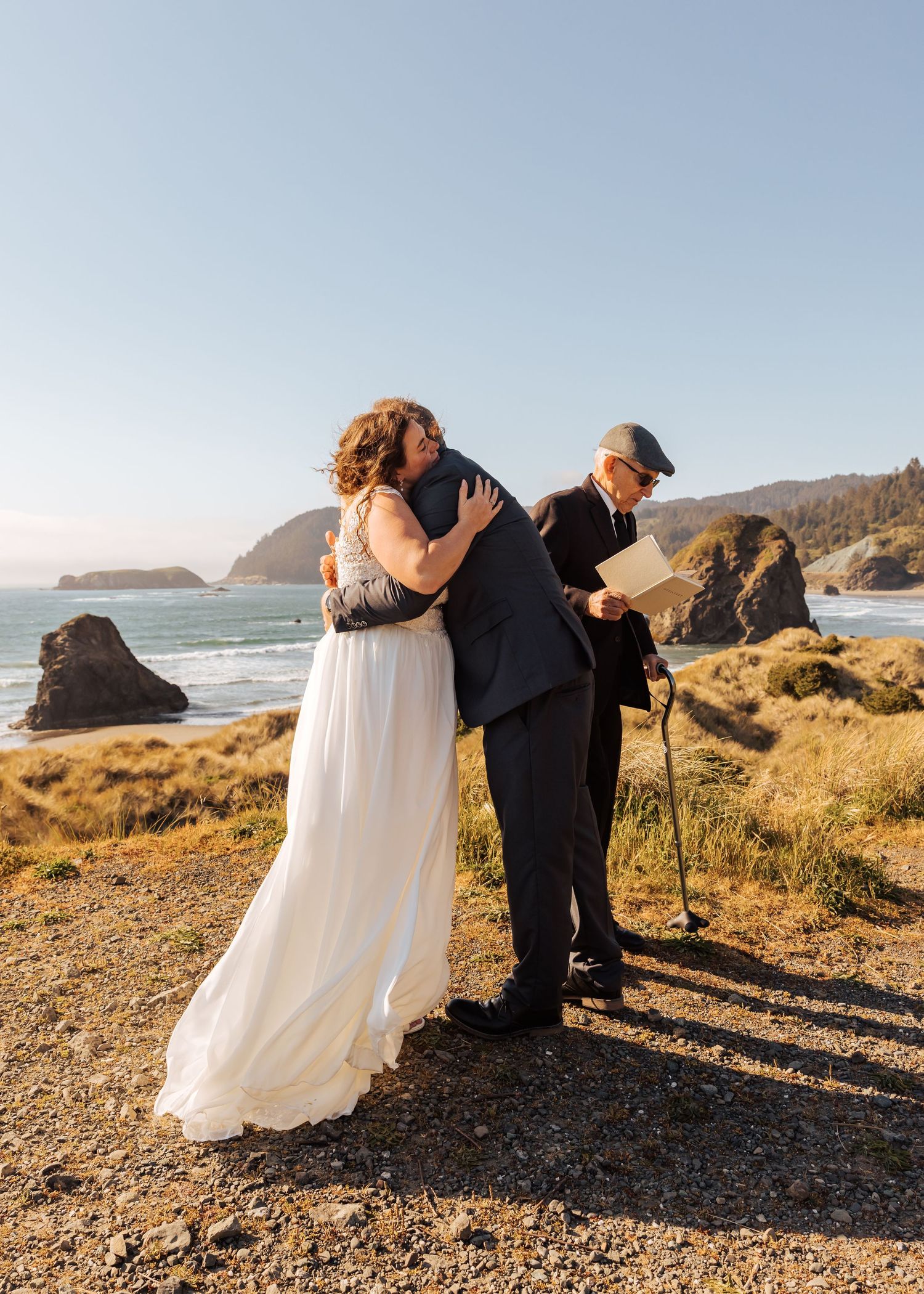 A couple shares their first moments as newlyweds against a dramatic coastal landscape.