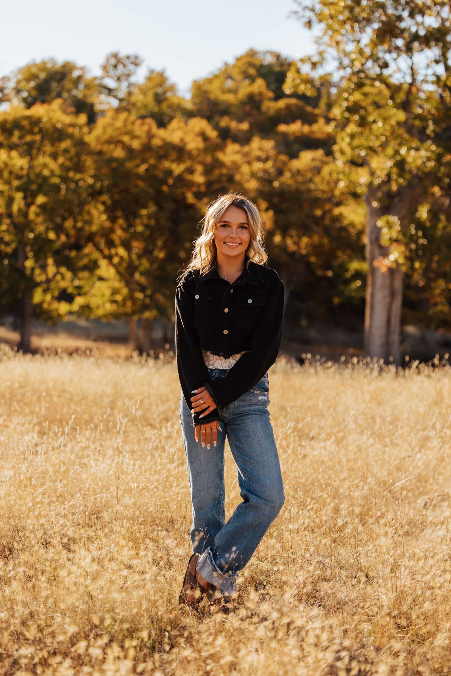 Dynamic poses captured in a golden field with autumn trees in background.