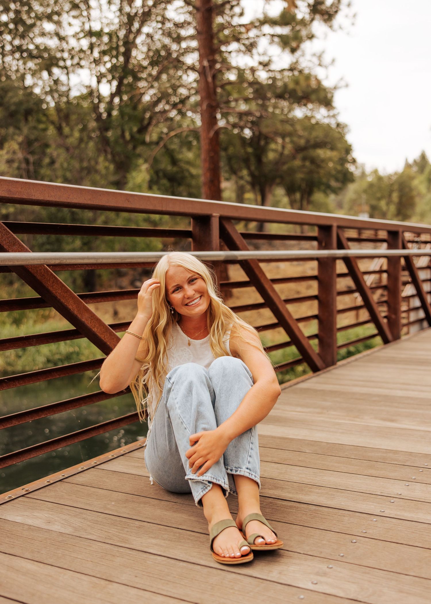 Casual outdoor photo session on a wooden boardwalk with light denim and sandals.