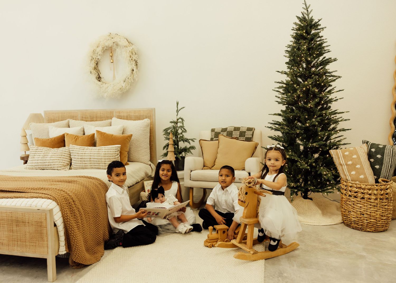 A cozy holiday scene with Christmas trees, woven baskets, and neutral furnishings in a bright studio space.