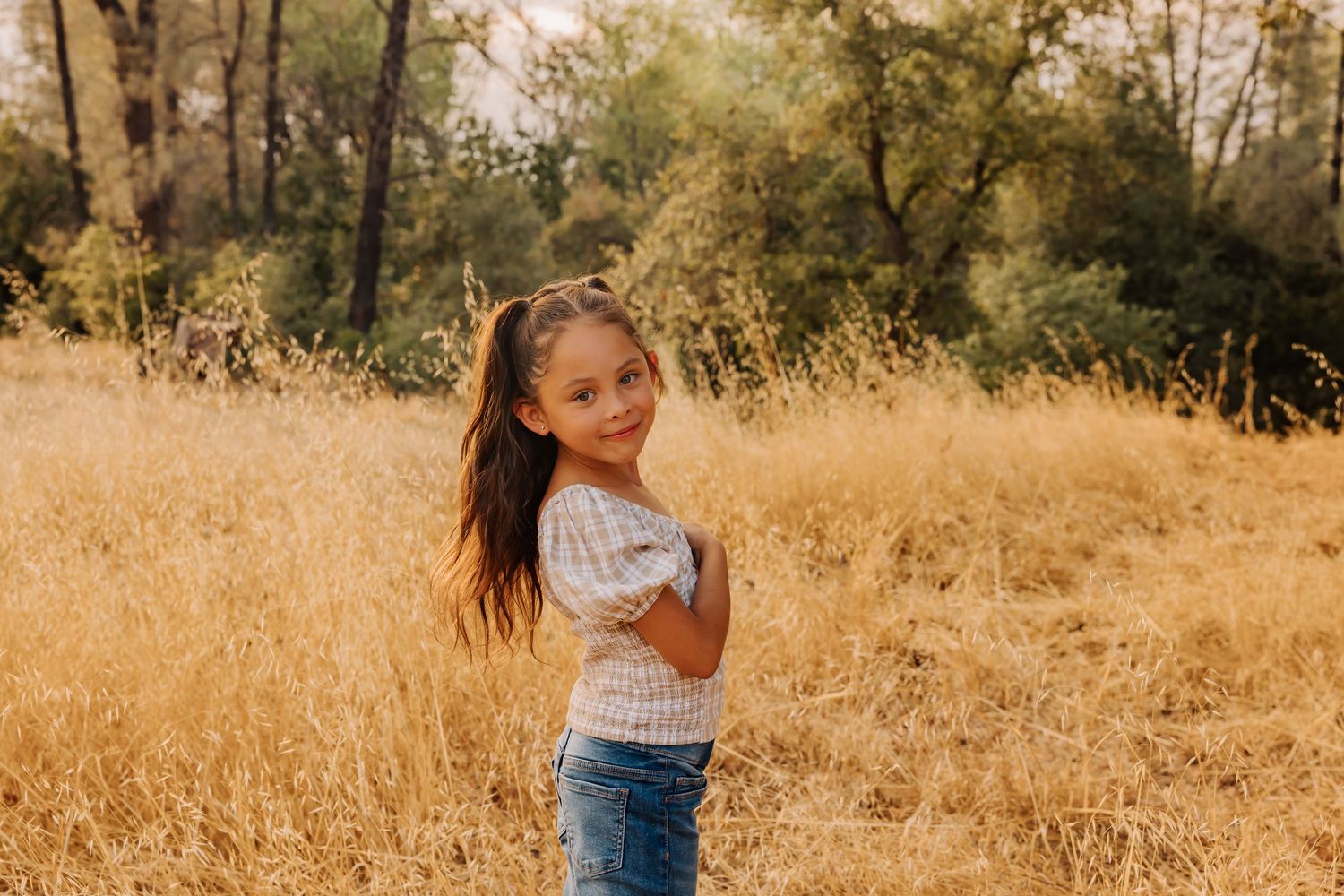 Children playing in golden field with trees in background.