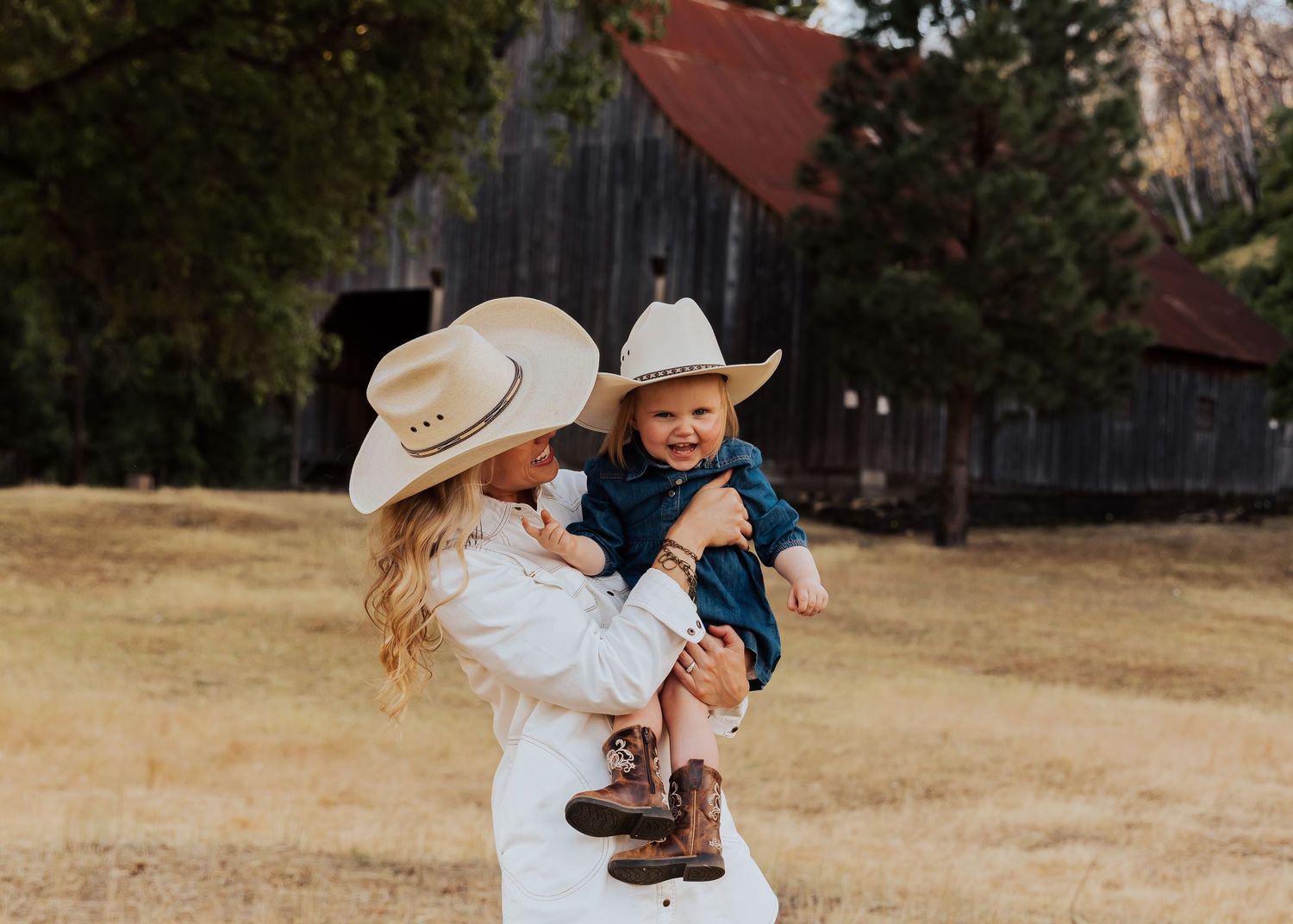 Couple embracing in front of a rustic wooden barn during a golden hour photoshoot.