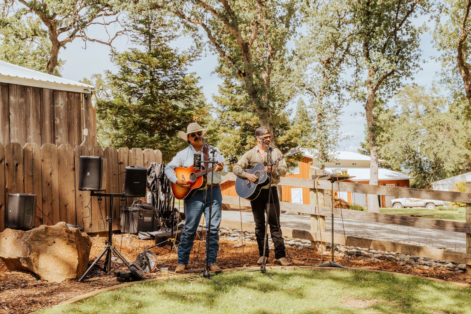 Musicians performing with guitars at an outdoor wedding venue.