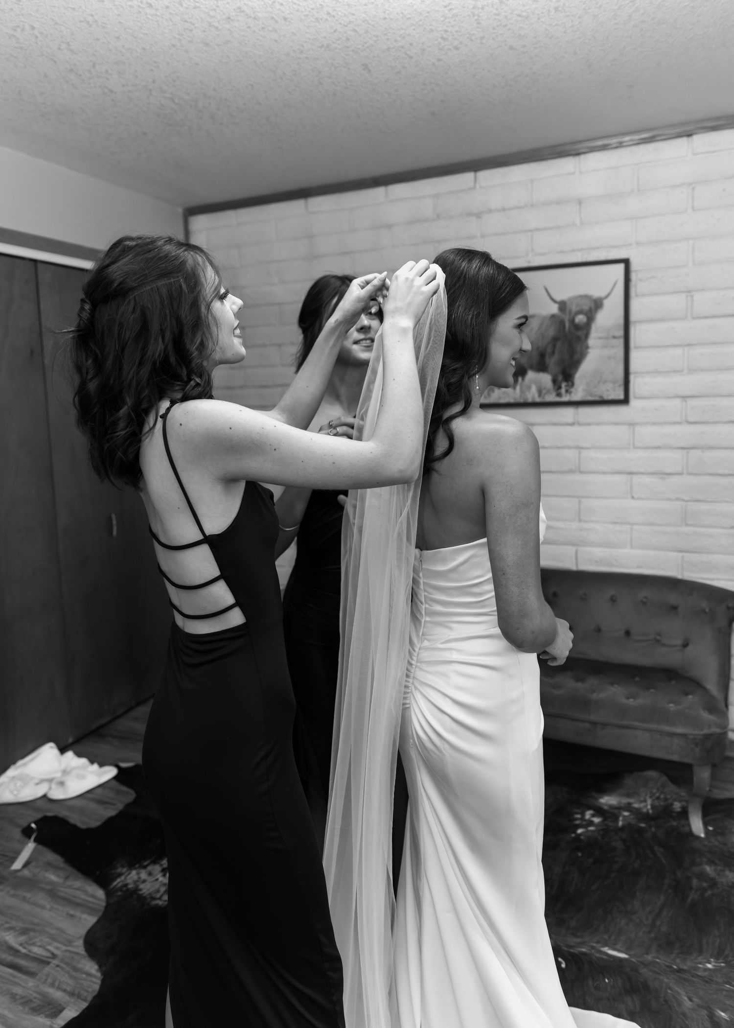 Wedding dress being adjusted and fitted in a room with white brick walls.